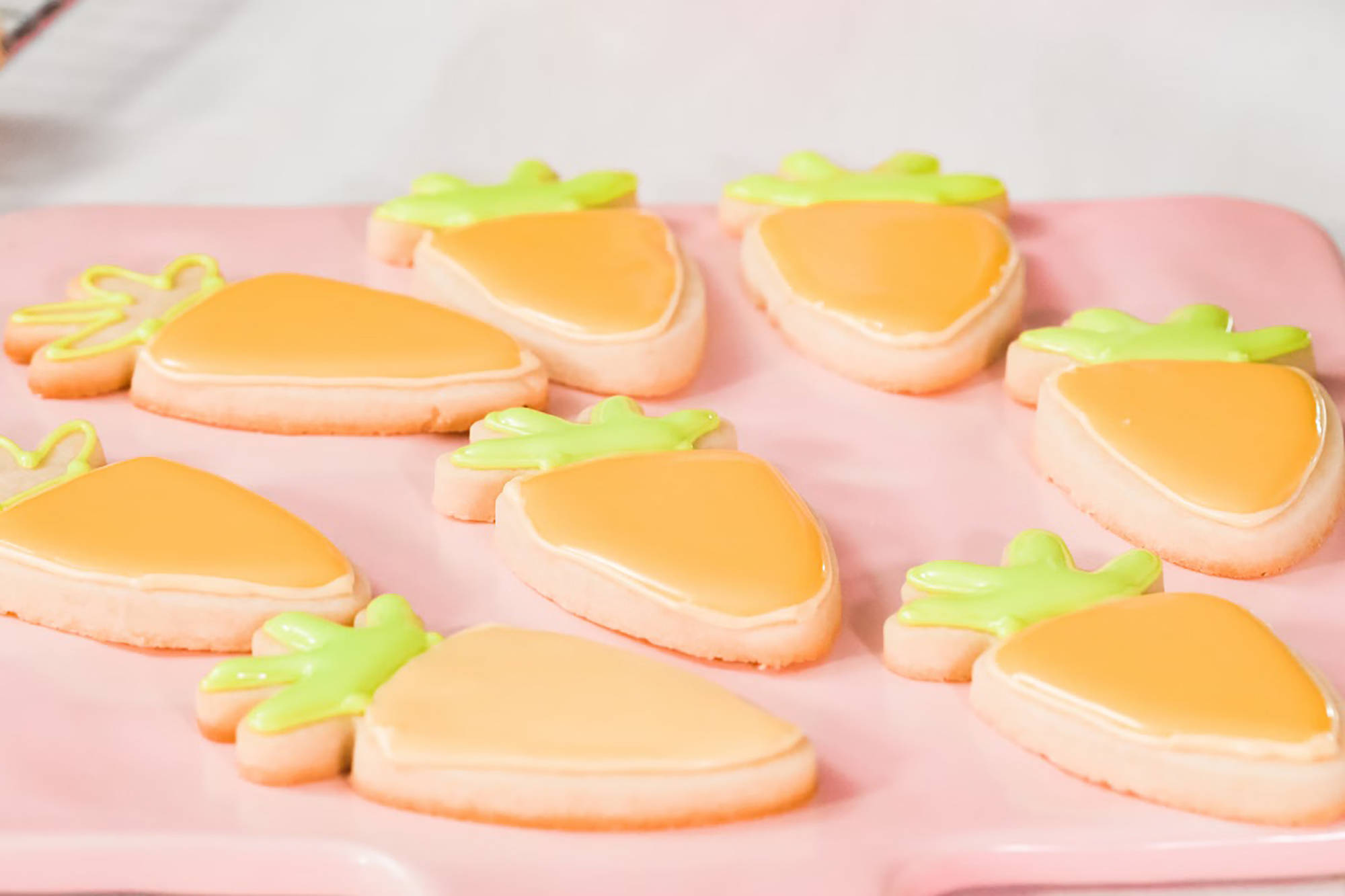 Plätzchen in Karottenform mit oranger und grüner Verzierung.