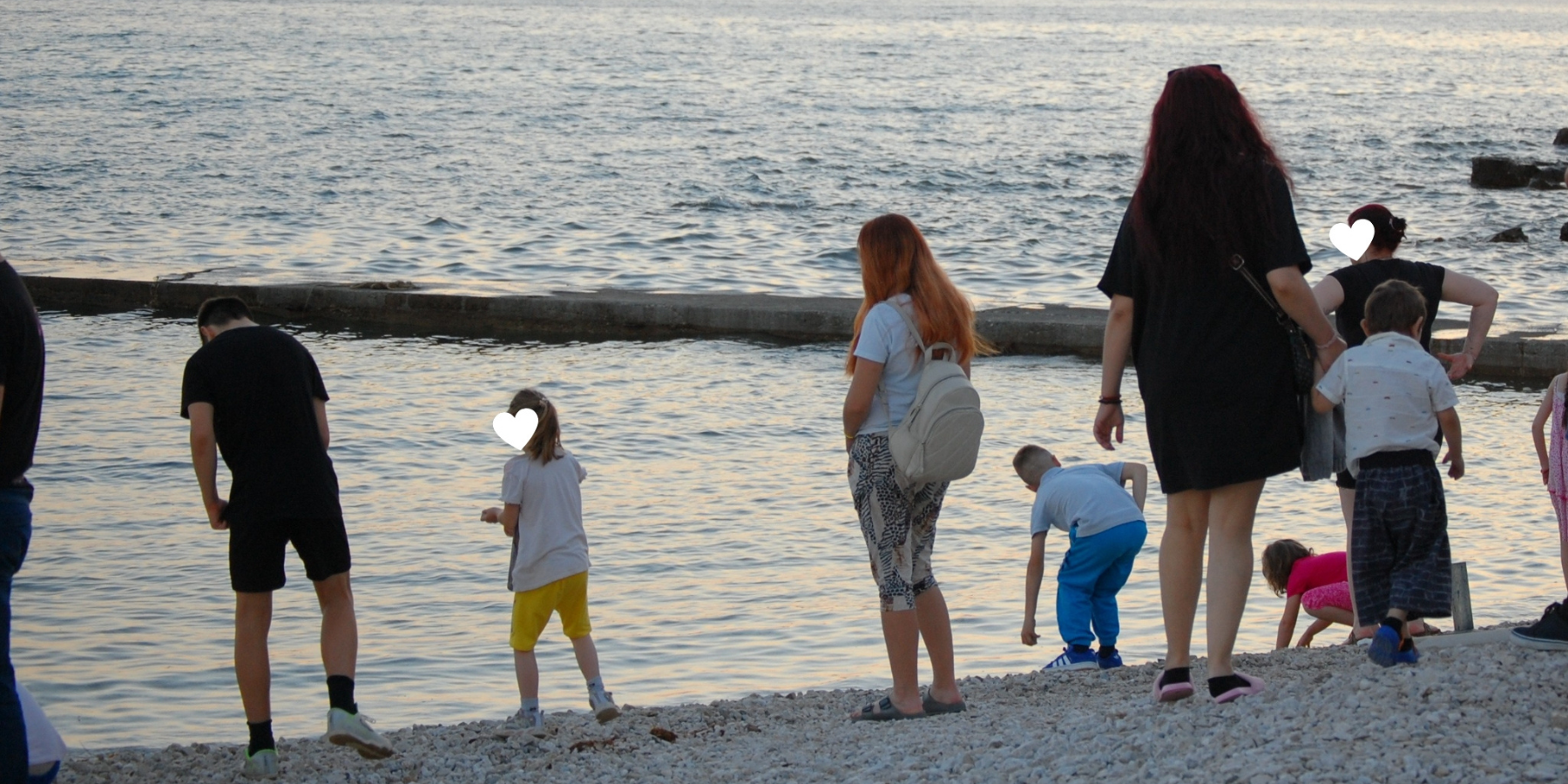 Družine stojijo na plaži ob morju