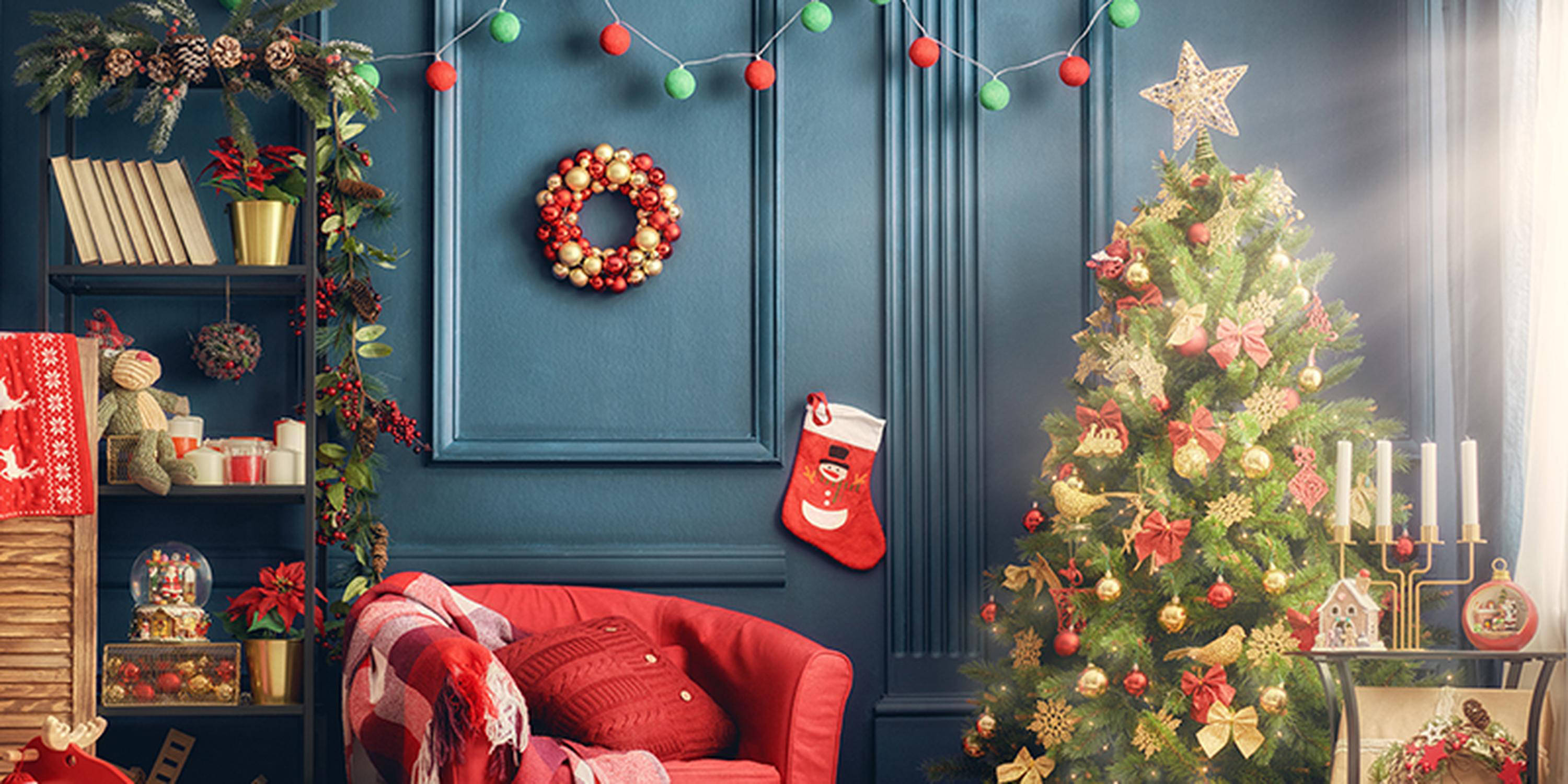 Weihnachtsdeko wie eine rote Socke, geschmückte Tannenzweige und ein Adventkranz hängen oder stehen vor einer blauen Wan