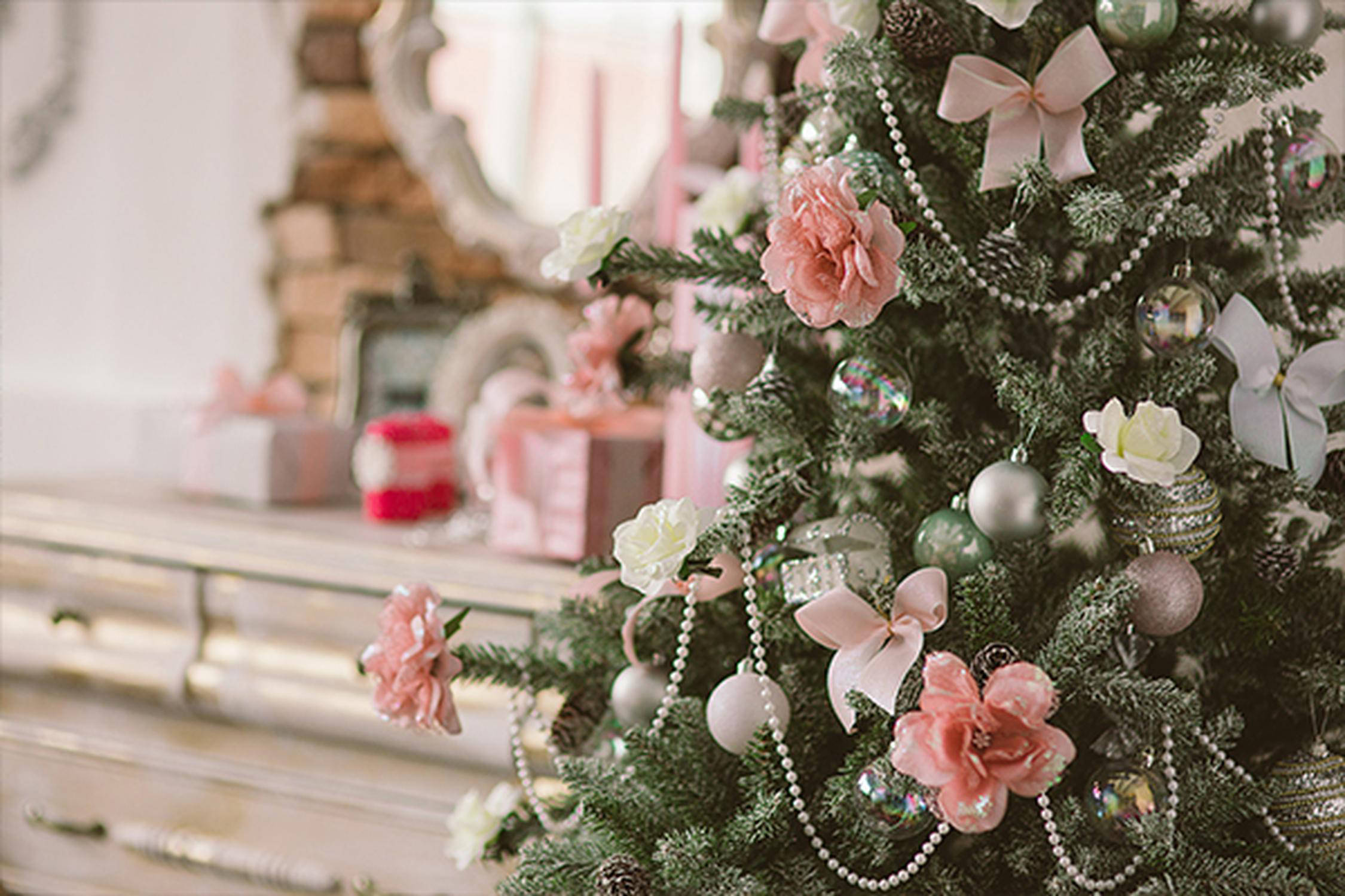 Ein lieblich geschmückter Christbaum mit rosa Blumen und Kugeln vor einem Schminktisch