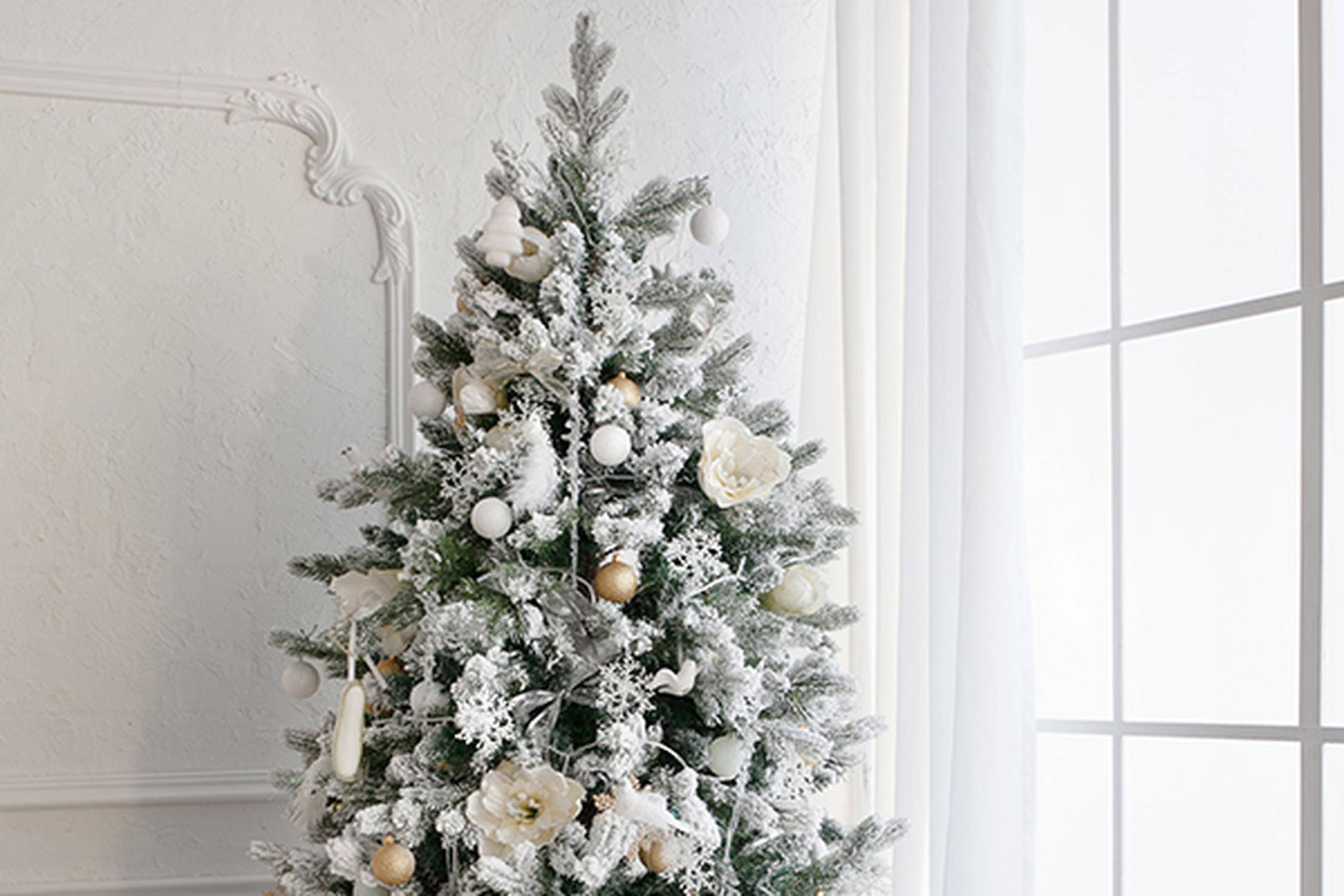 Christbaum mit weißem Schmuck und Sprühschnee bedeckt