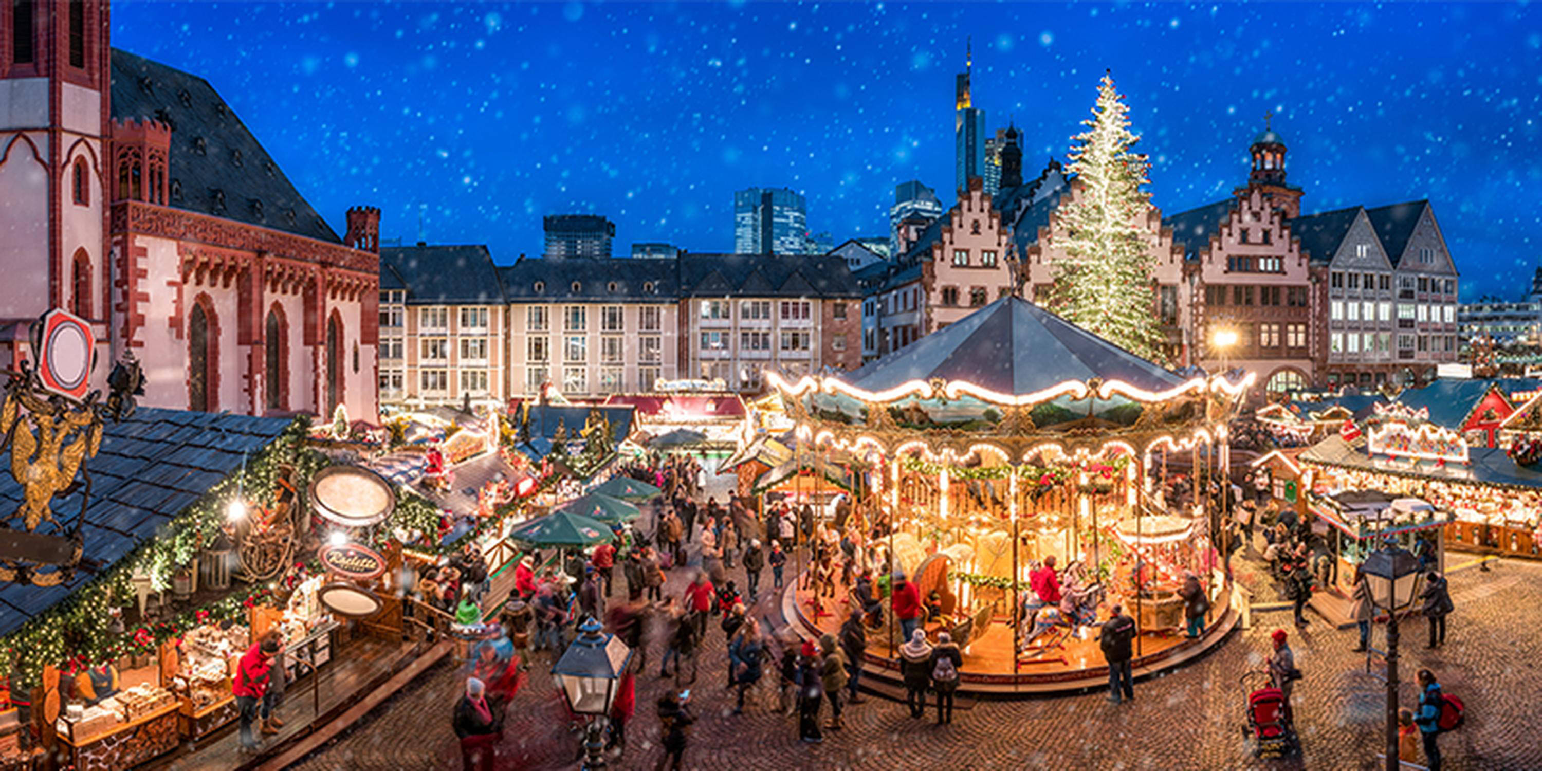 beleuchtetes Karussell auf einem Christkindlmarkt mit Menschen davor