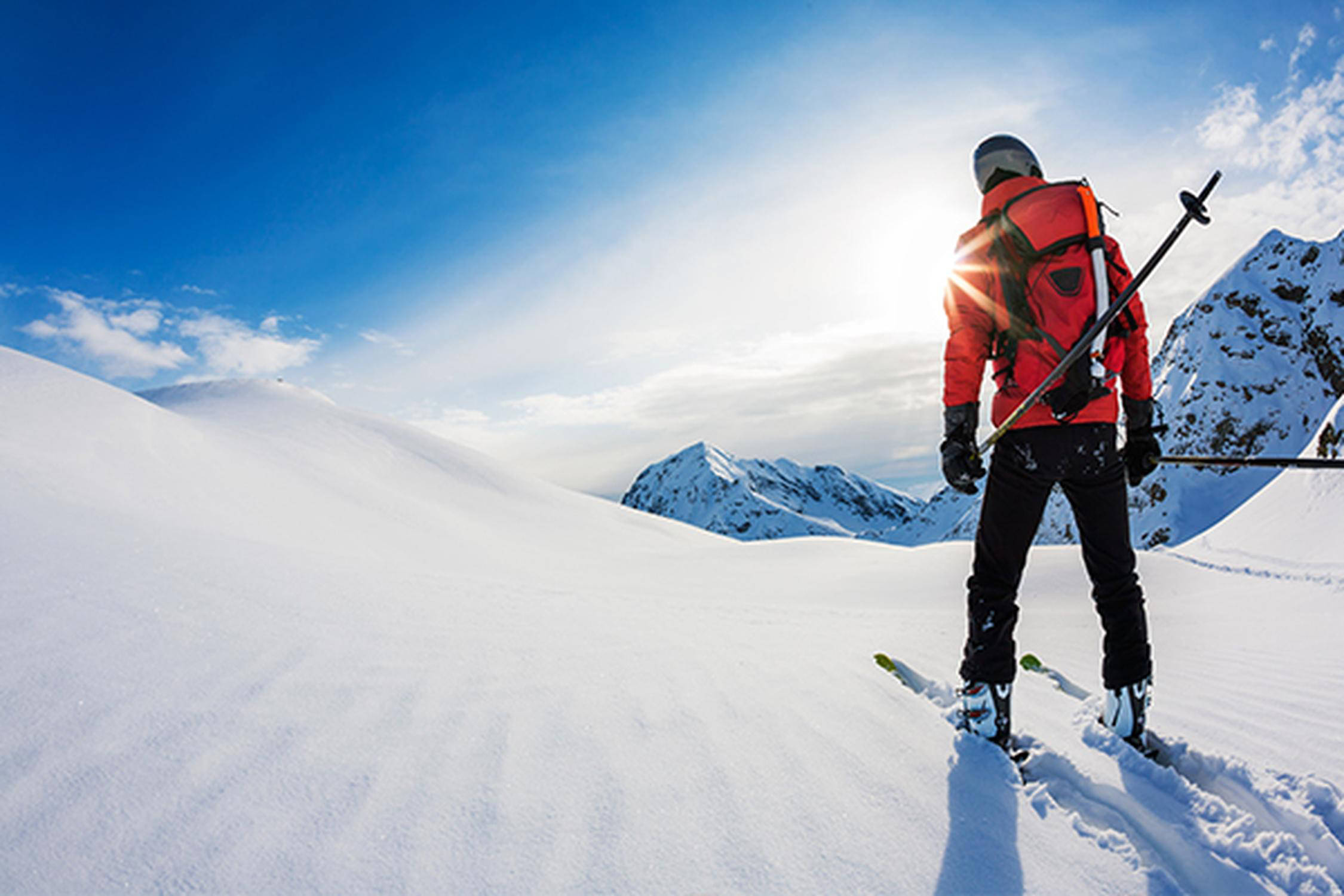 Skifahrer mit einer roten Jacke fährt auf einer Skipiste