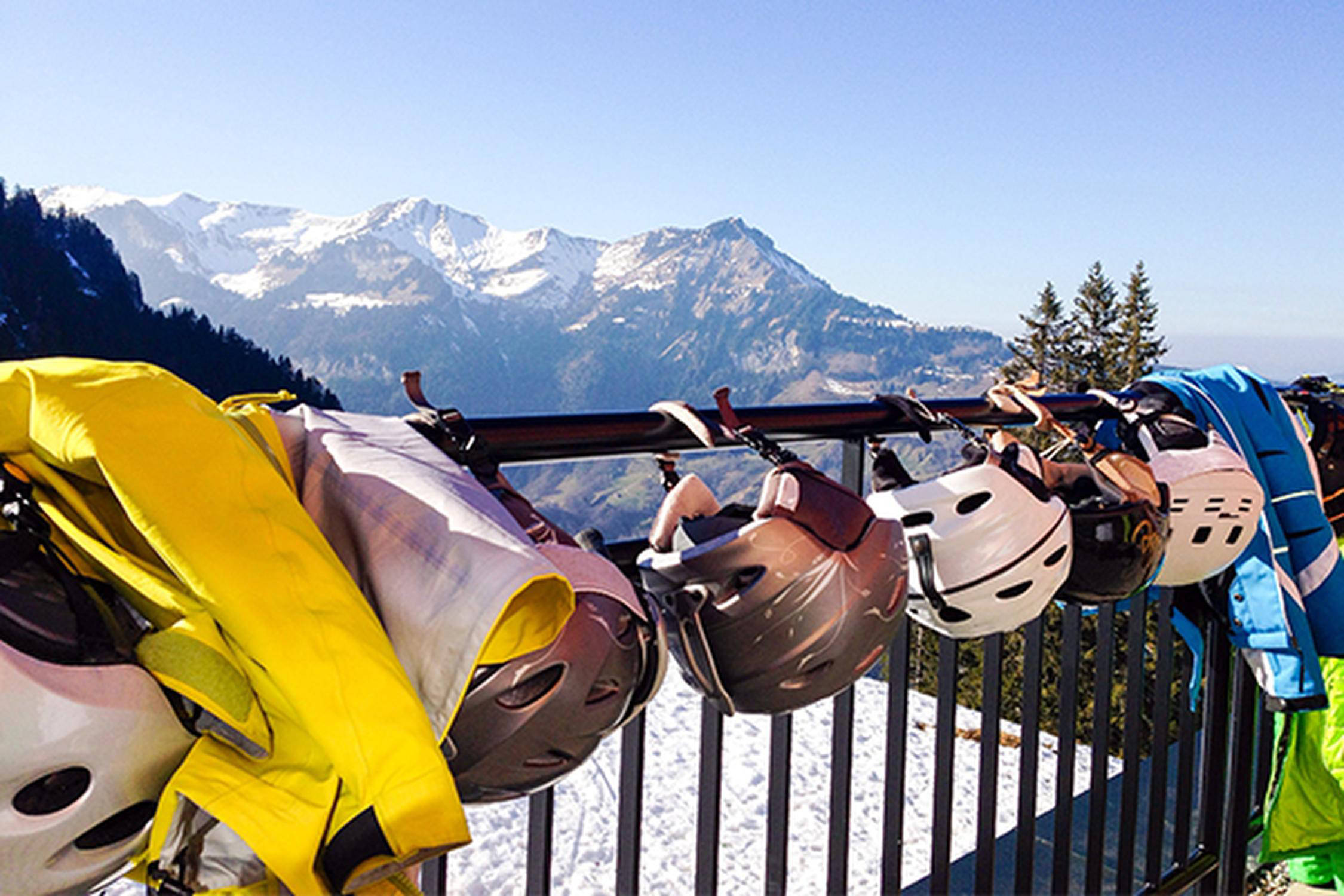 sechs Skihelme hängen an einem Geländer