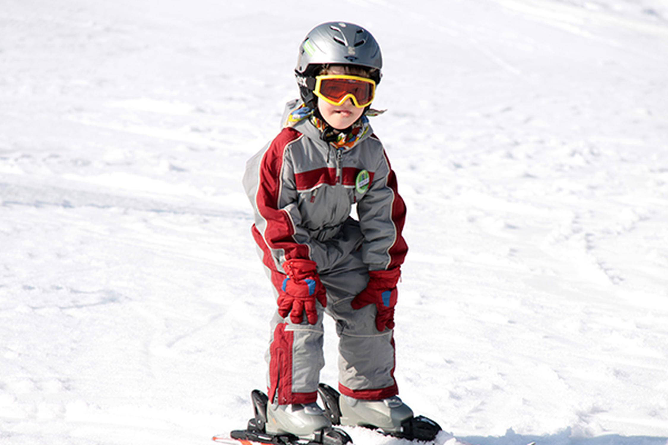Kleinkind mit einem Helm und Skibrille fährt auf Ski
