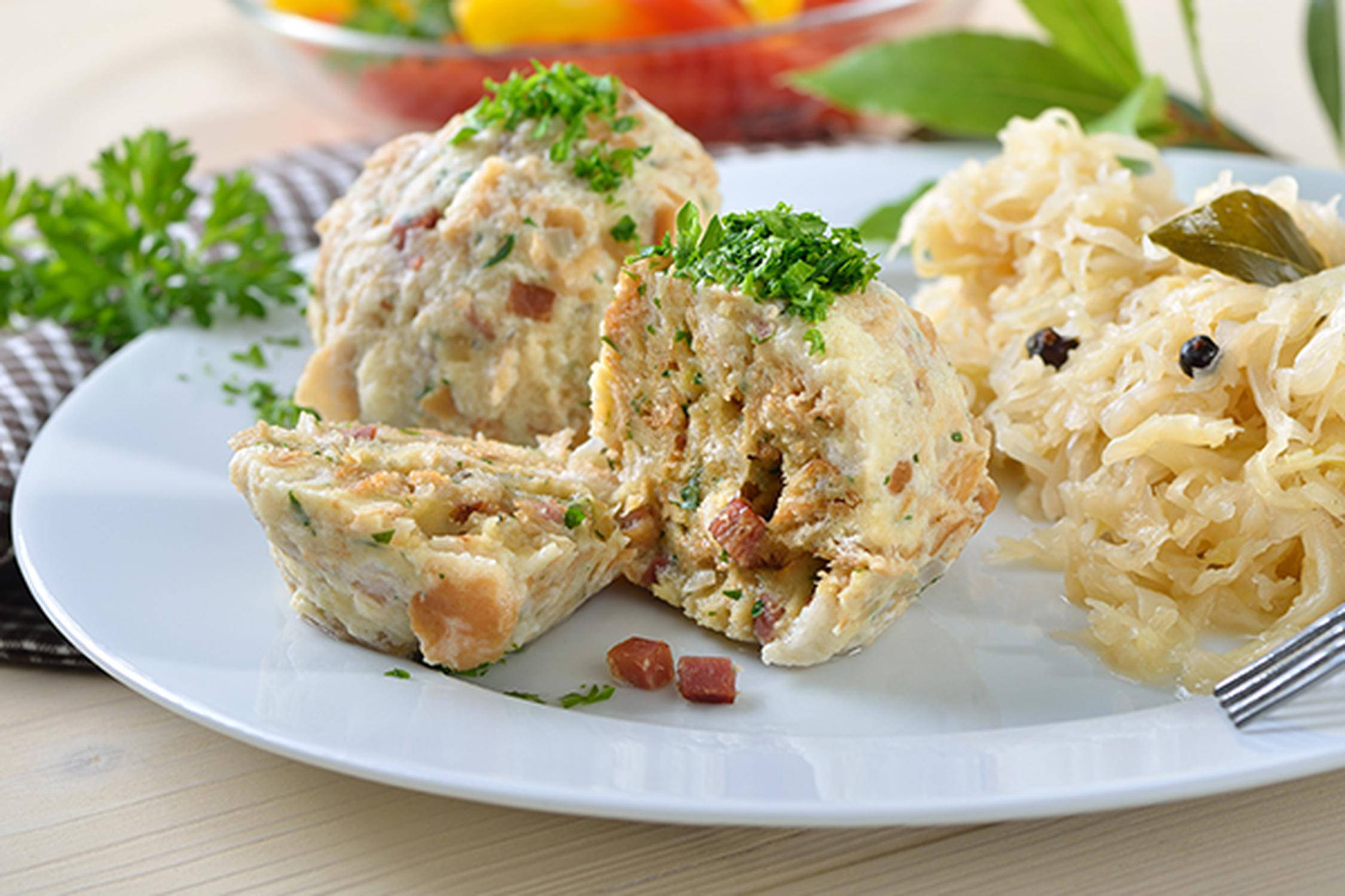 Speckknödel mit Kraut liegen auf einem weißen Teller