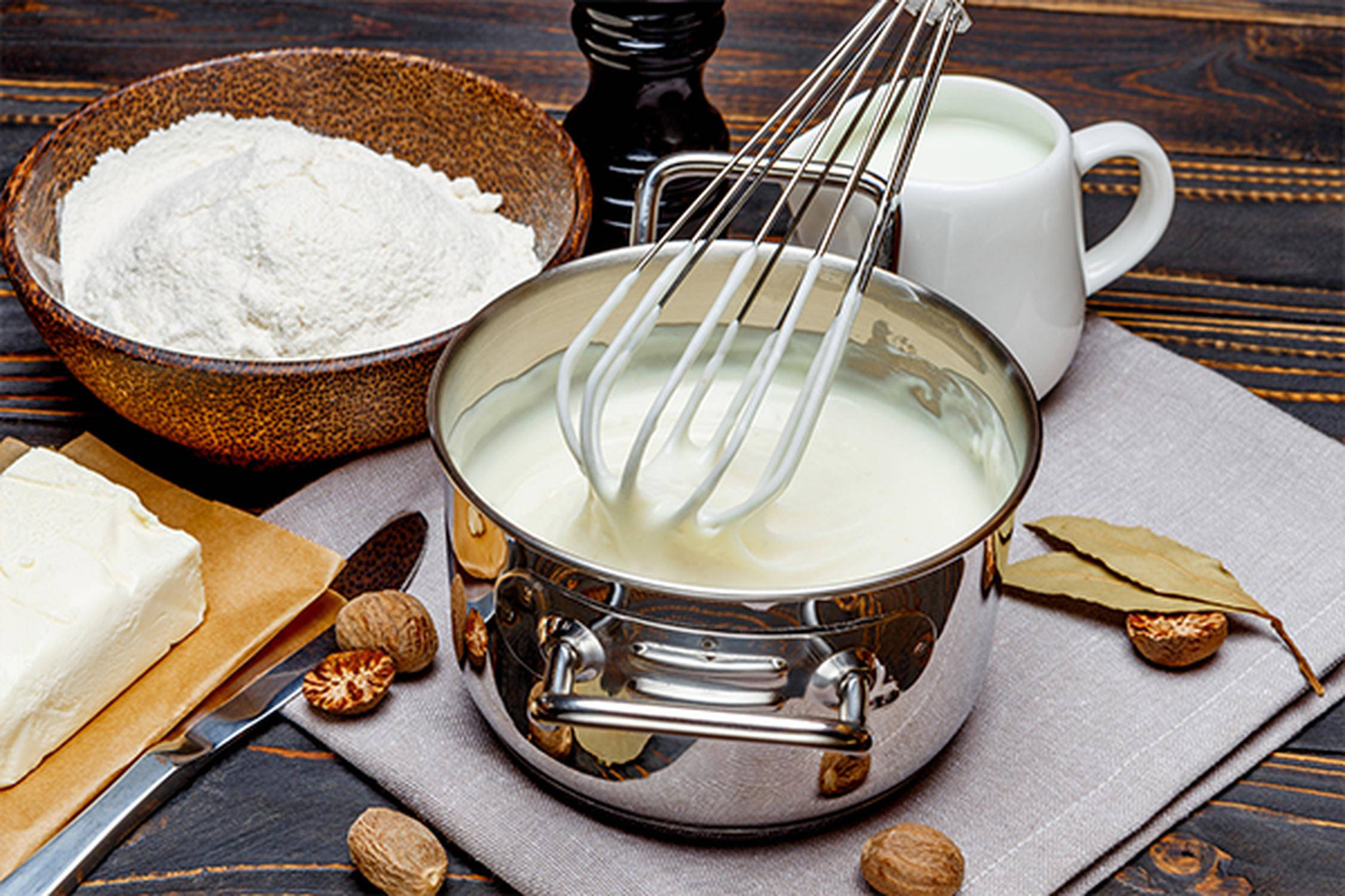 Kochtopf mit Sauce Bechamel und einem Rührbesen darin