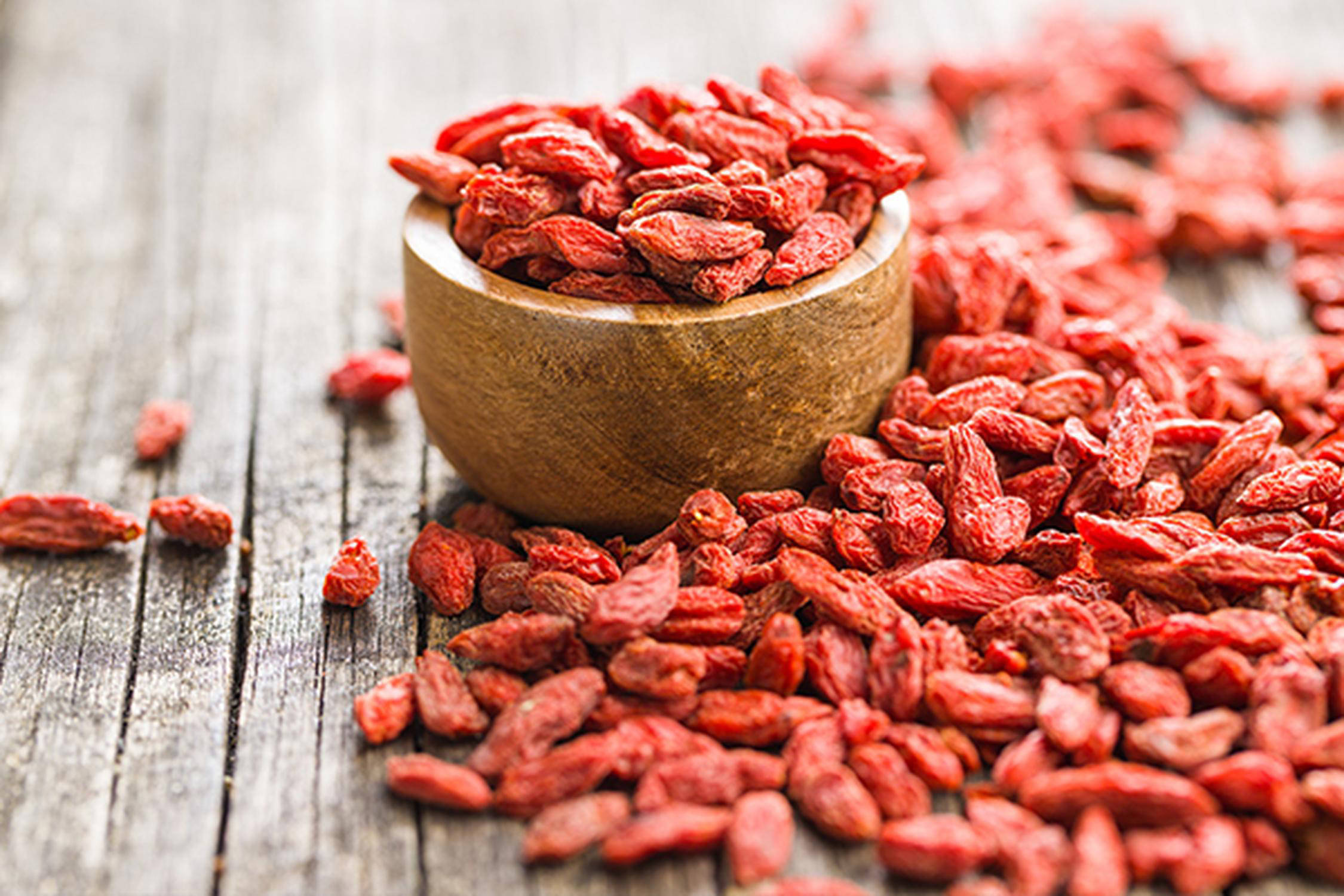 Goji-Beeren auf einem Holztisch und in einer Holzschüssel