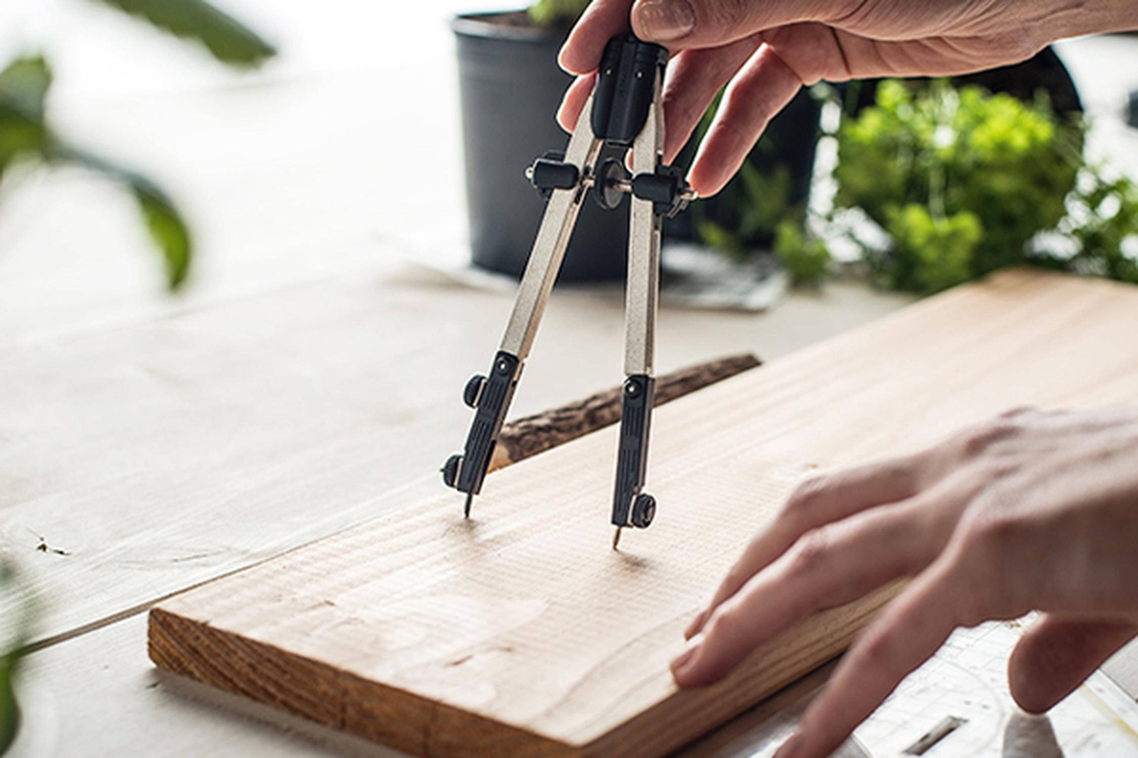 Es wird mit einem Zirkel ein Kreis auf einer Holzplatte angezeichnet