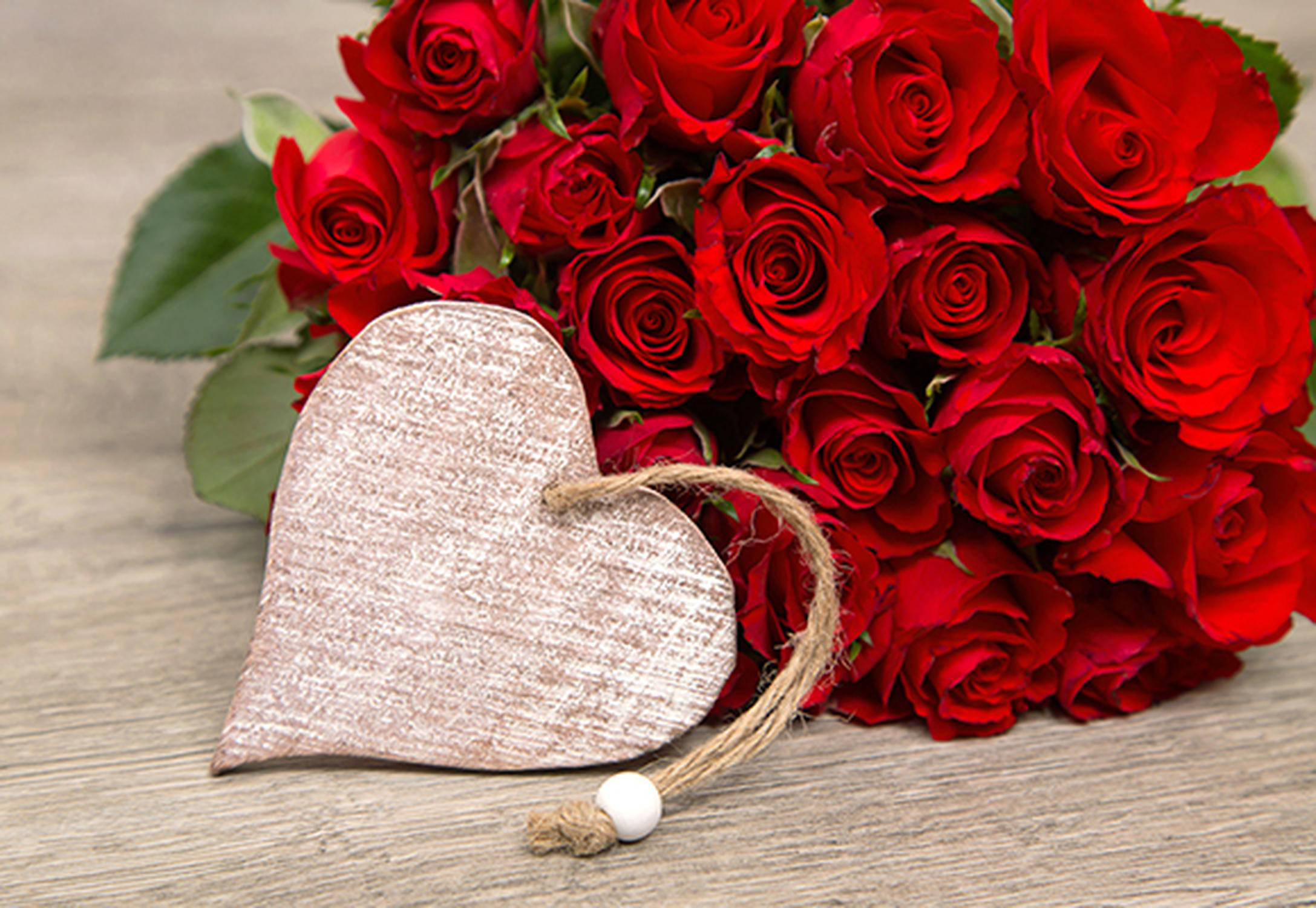 Strauß rote Rosen mit einem Tonherz im Vordergrund