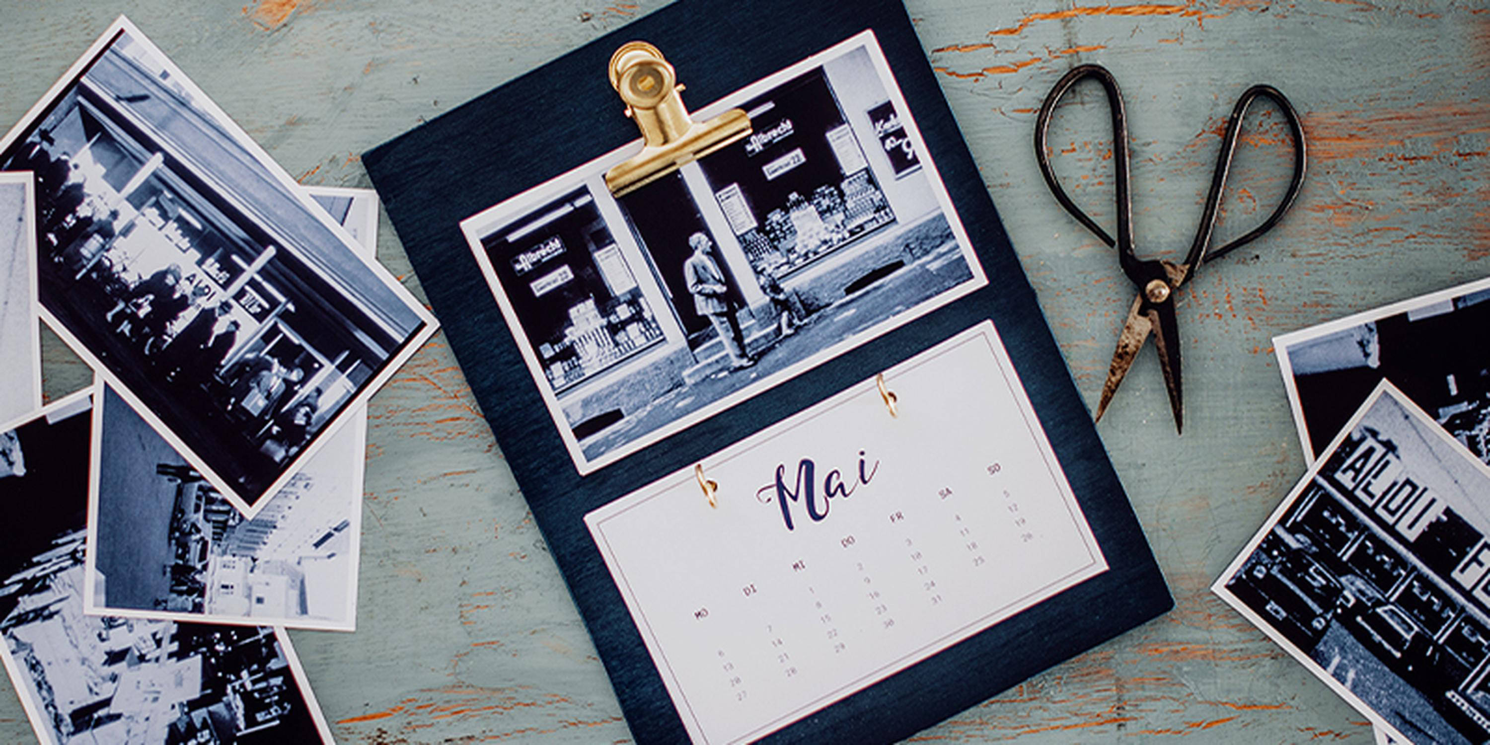 Fotokalender und Fotos mit einer Schere liegen nebeneinander