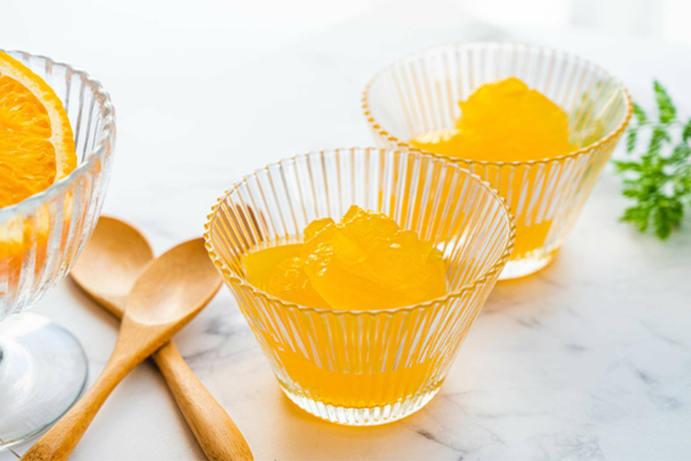 zwei Gläser mit oranger Gelatine gefüllt und zwei Holzkochlöffel liegen davor