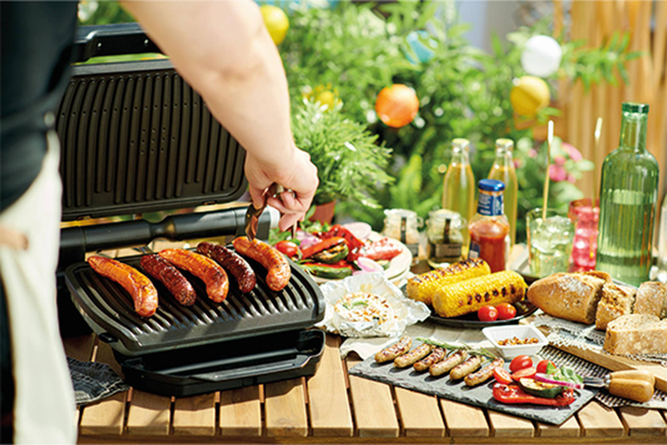 Auf dem Bild sieht man wie Würstchen auf einem Elektrogrill gegrillt werden.