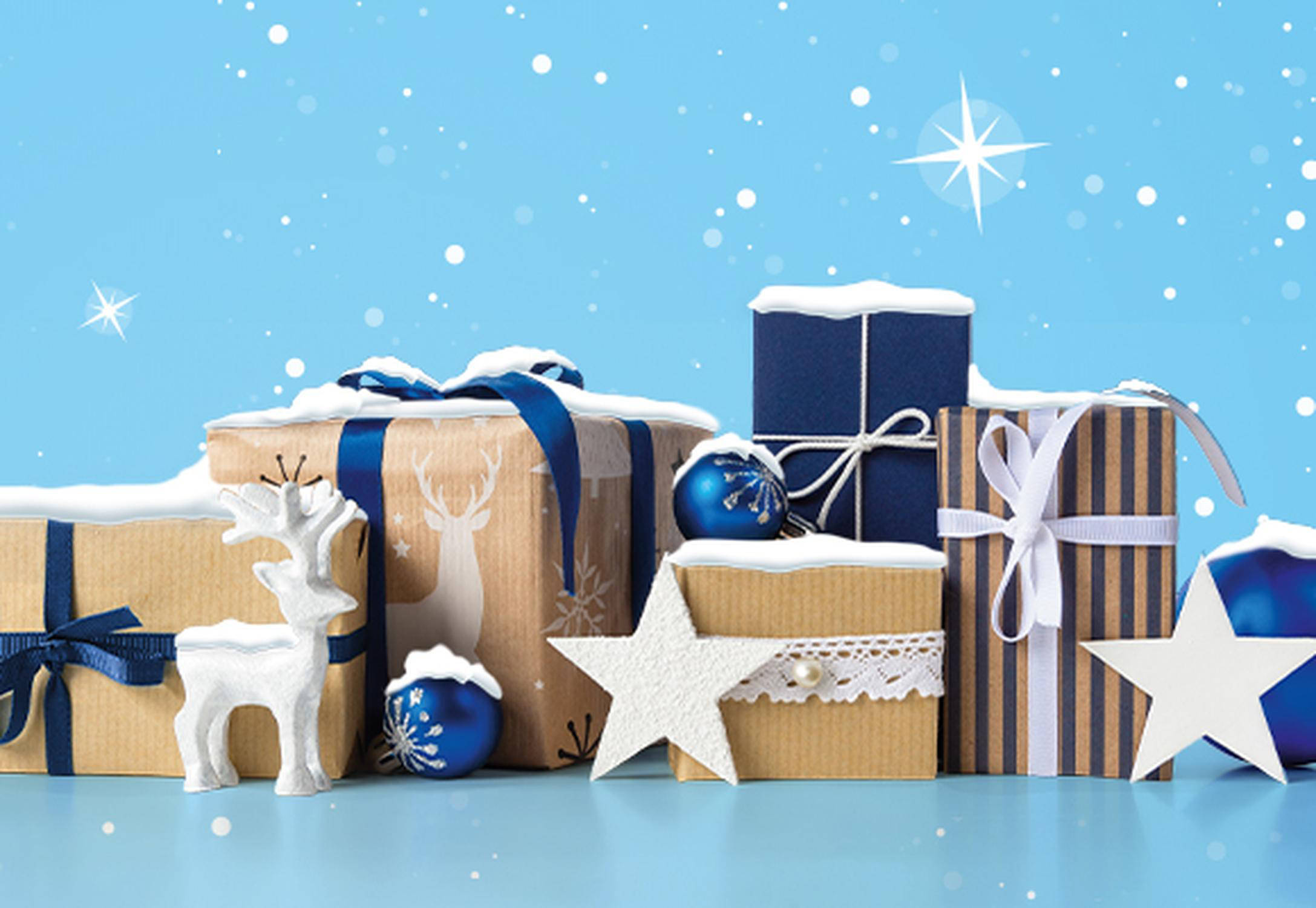 Geschenke und Deko auf blauem Hintergrund mit Schneeflocken und Sternen, festliche Winterstimmung.