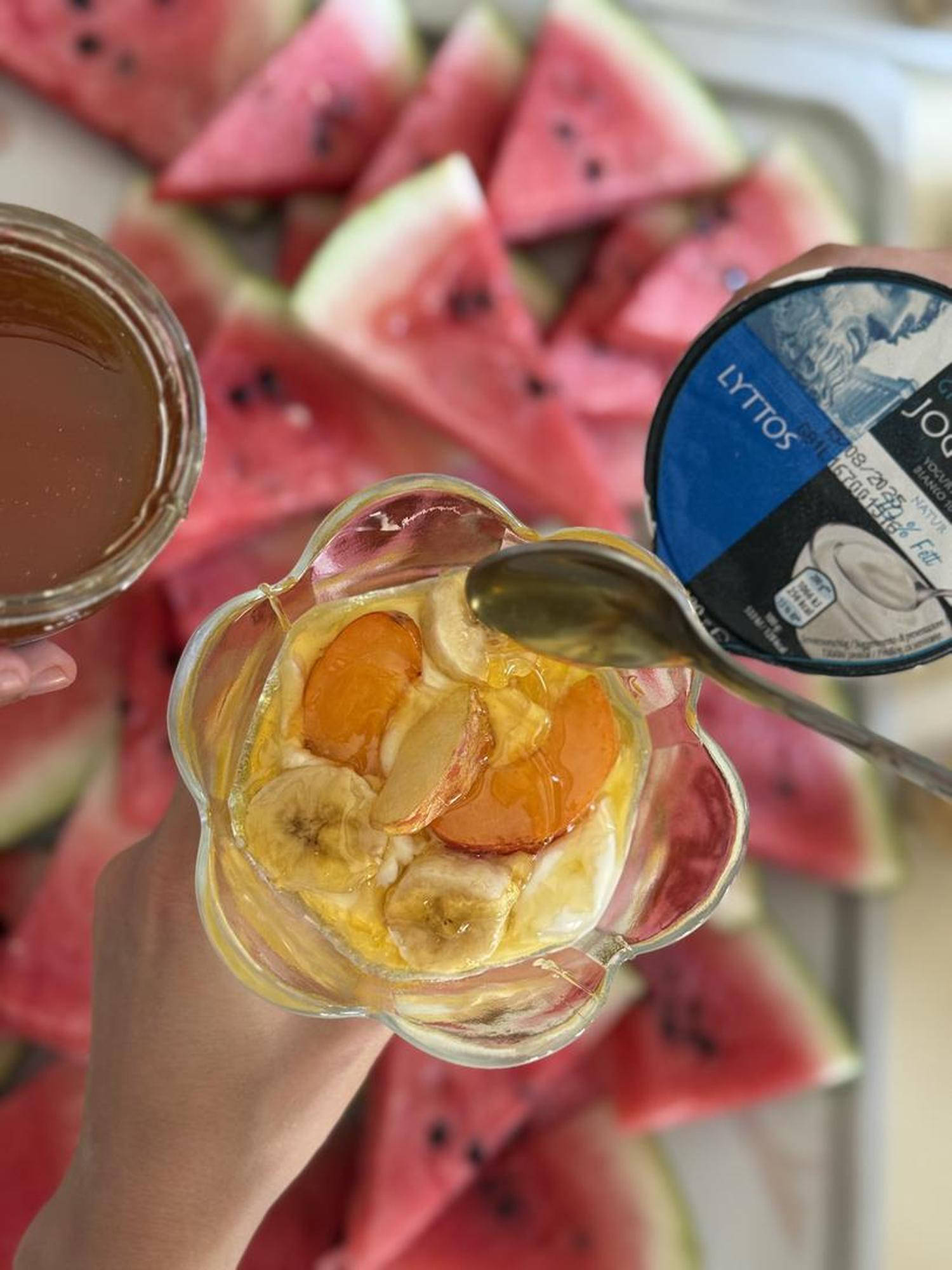 Lubenica, grški jogurt in steklen kozarec s sadno kupo v otroških rokah