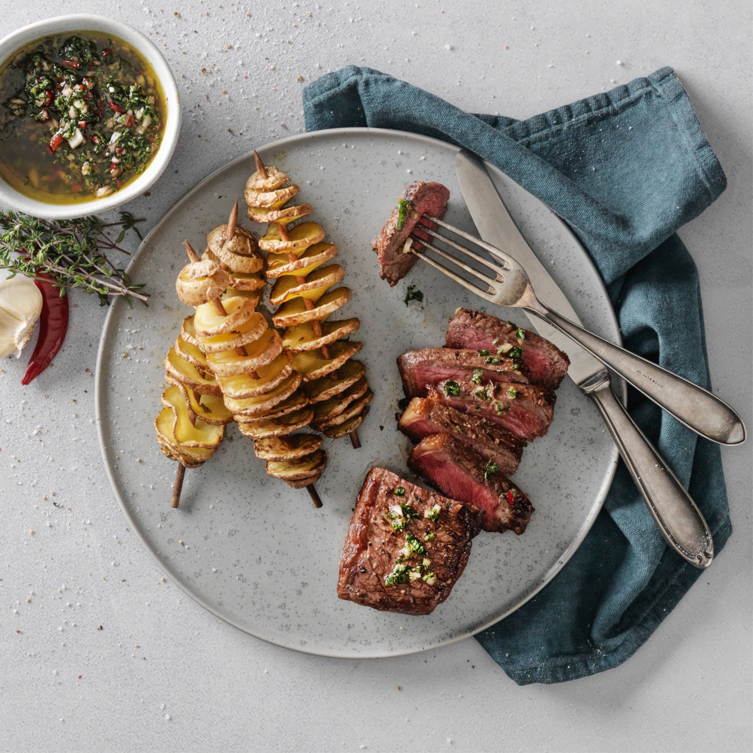 Serviervorschlag: Rosa grilliertes Rindsentrecôte mit Fächerkartoffeln und Chimichurri-Sauce