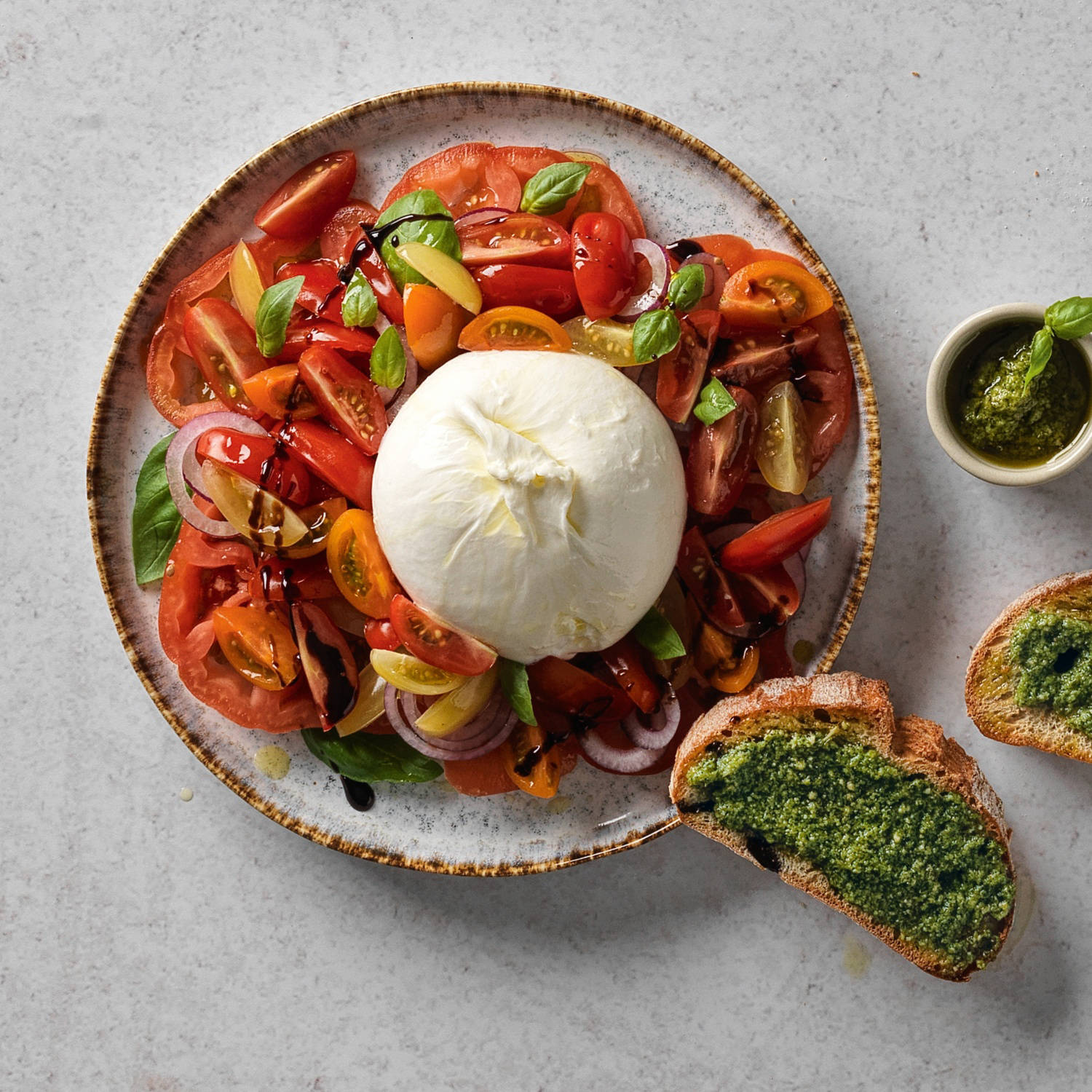 Serviervorschlag: Bunter Tomatensalat mit Burrata und knusprigem Pesto-Bruschetta