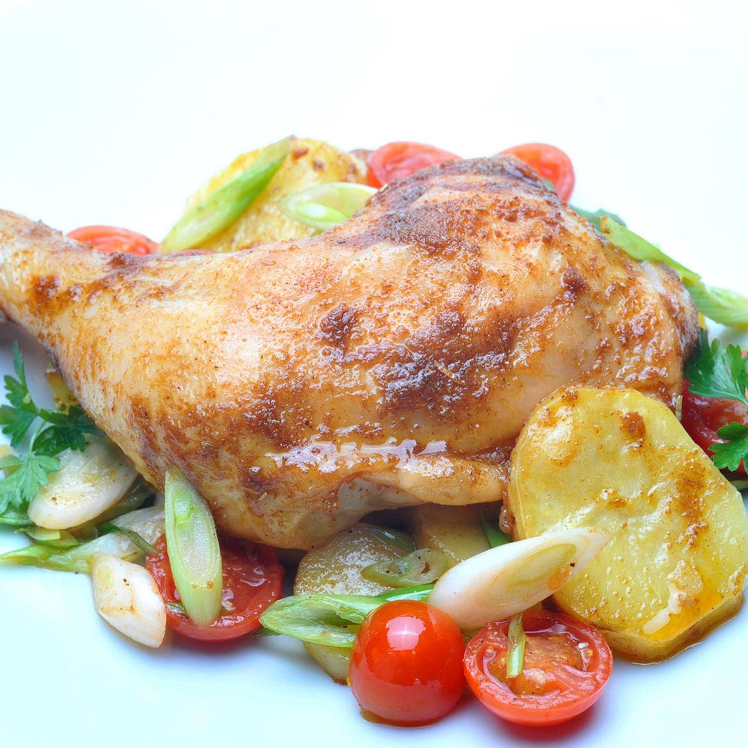 Serviervorschlag: Gebratene Hähnchenkeulen auf Kartoffeln mit Tomatenscheiben