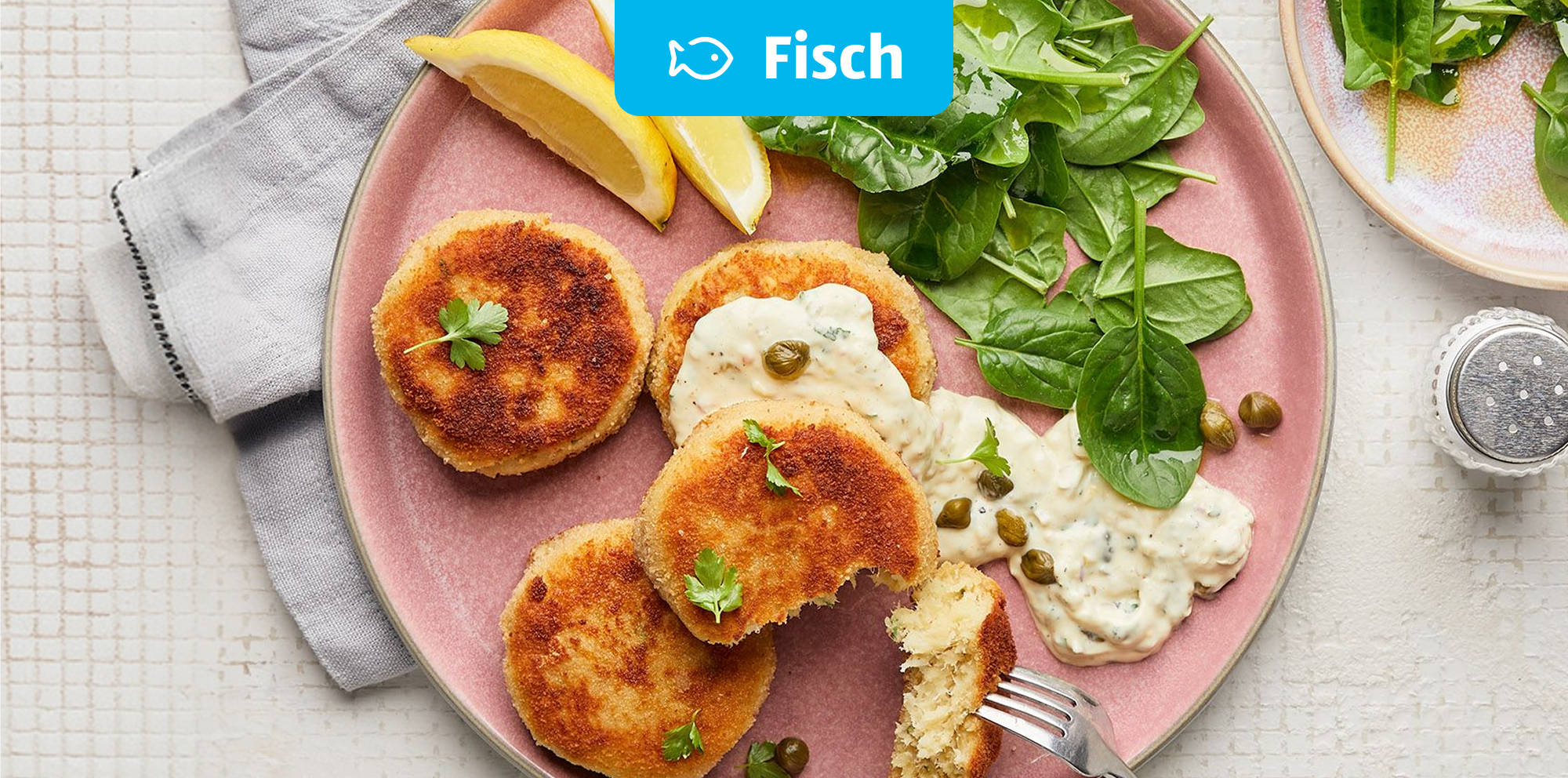 Knusprige Fischfrikadellen mit Salat und Soße.