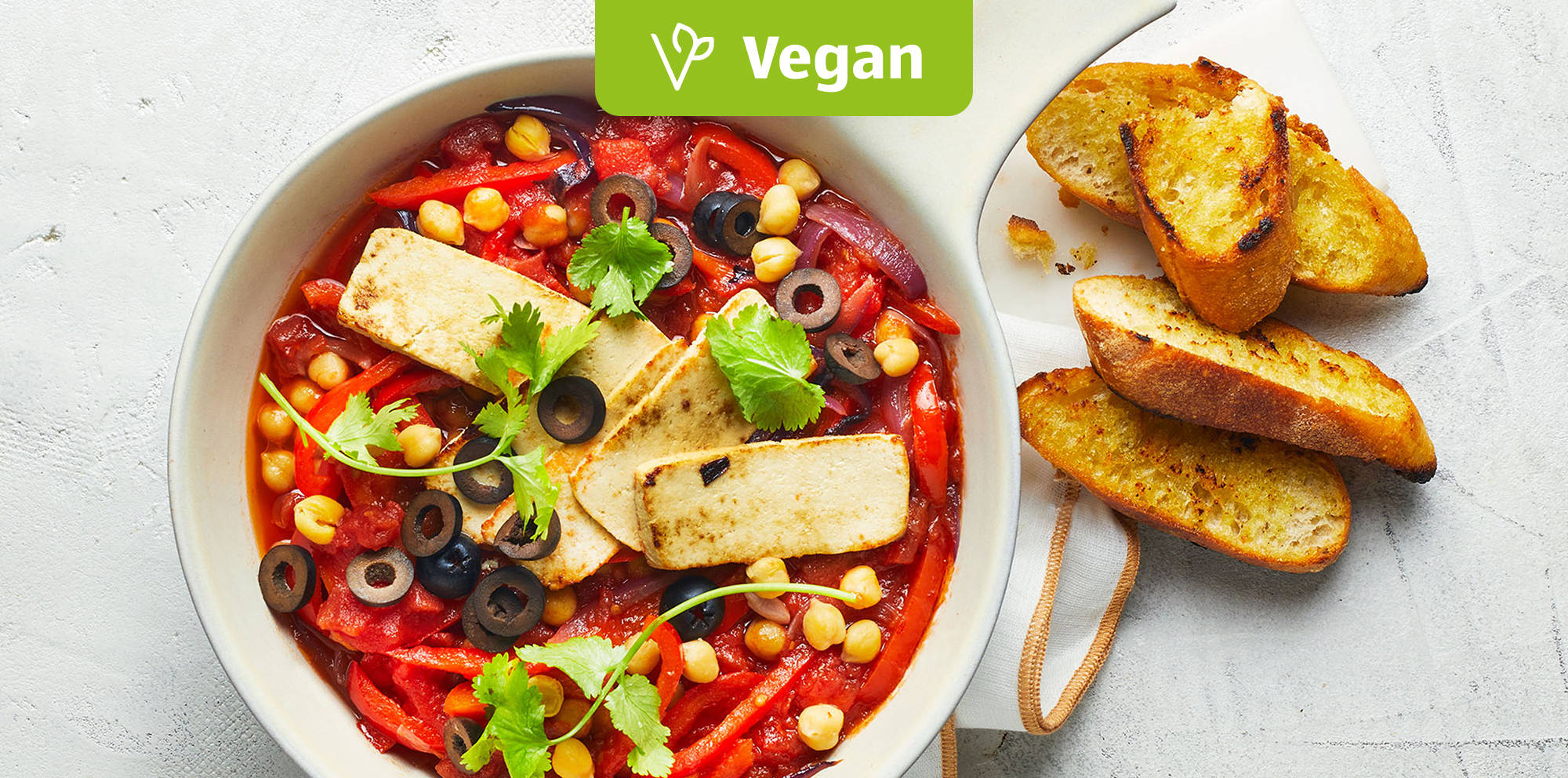 Bunte vegane Eintopf-Bowl mit Tofu und Brot.