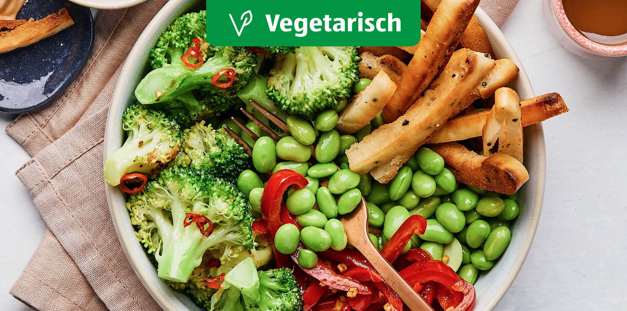 Colorful vegetarian bowl with vegetables and breadsticks.