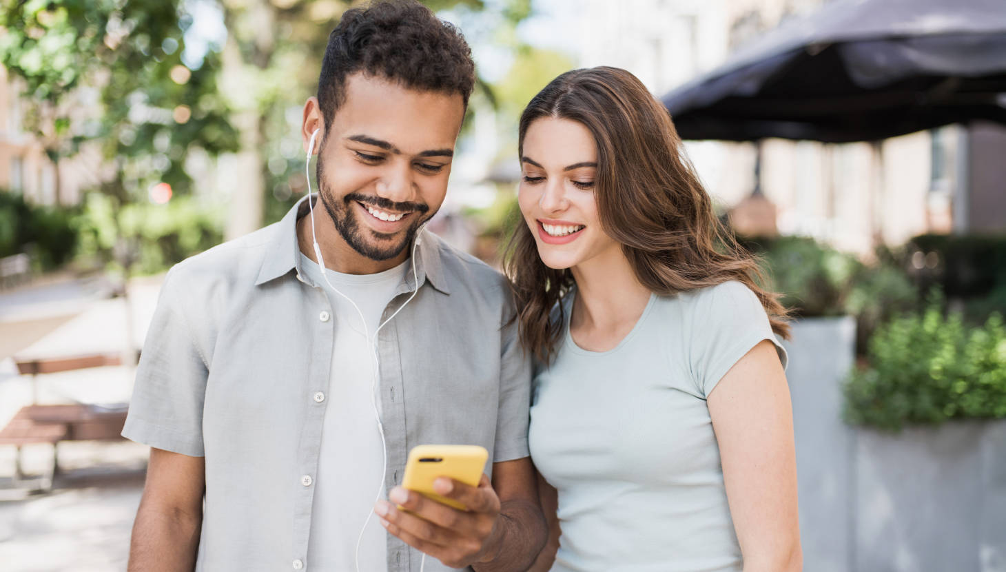 Frau und Mann stehen auf dem Gehweg und schauen auf ein Handy