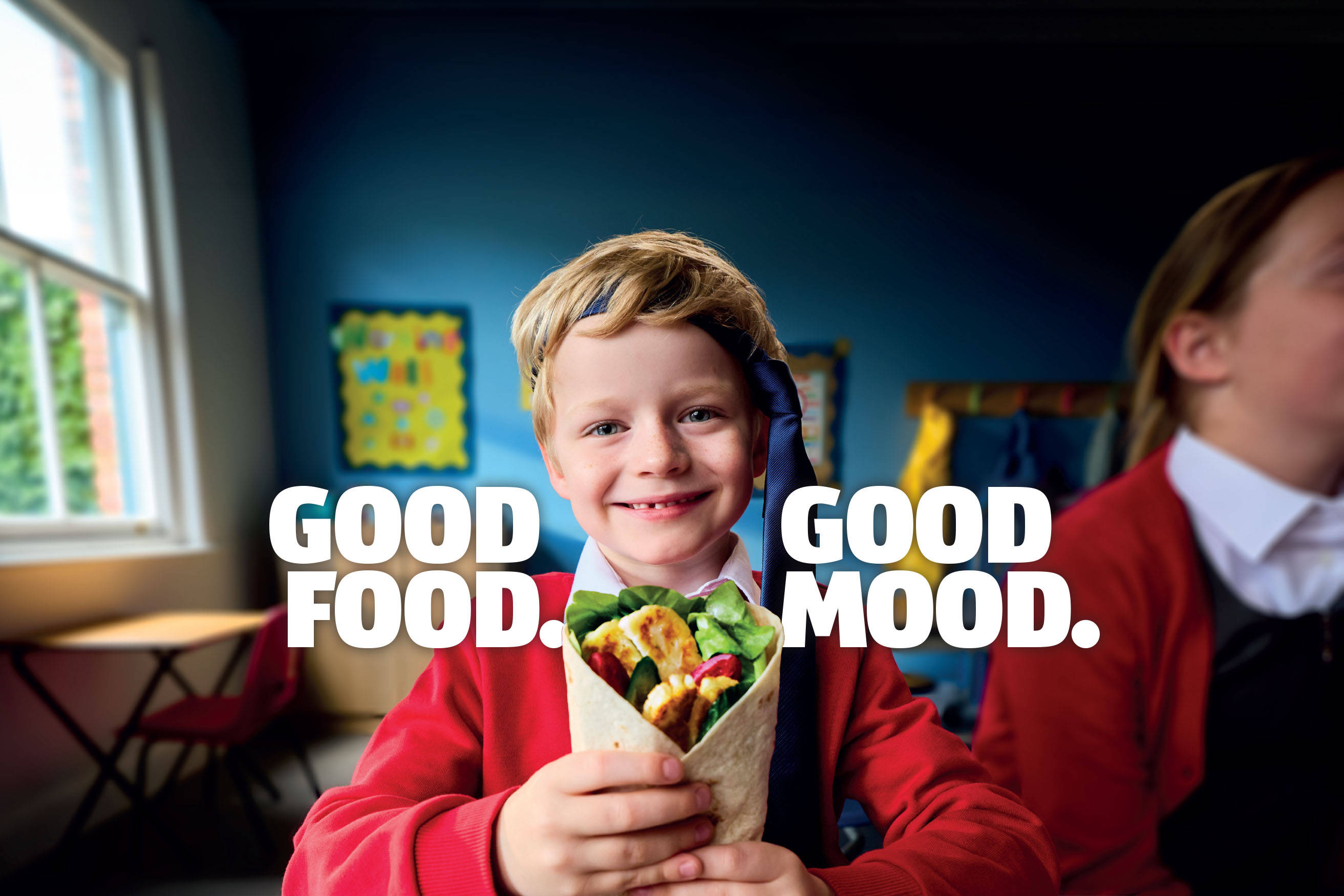 Students enjoying a meal together in a cheerful school setting, with copy saying Good Food, Good Mood