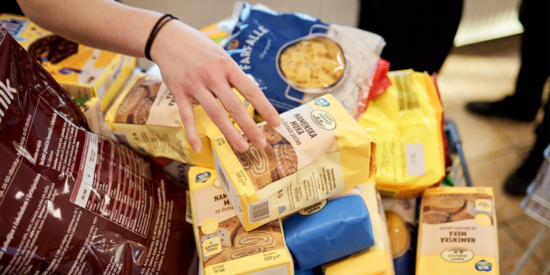 Hrana v embalaži v ozadju, napis: Doniramo presežno hrano.