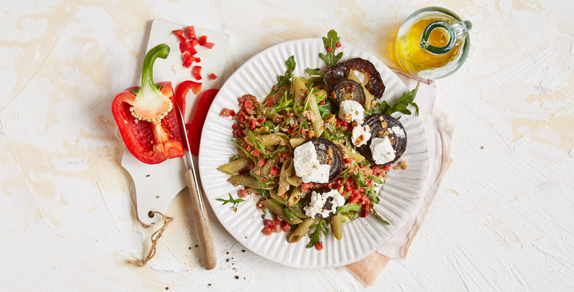 Serviervorschlag: Grüne-Erbsen-Penne mit gebackenen Zwiebeln und Walnuss-Paprika-Salsa