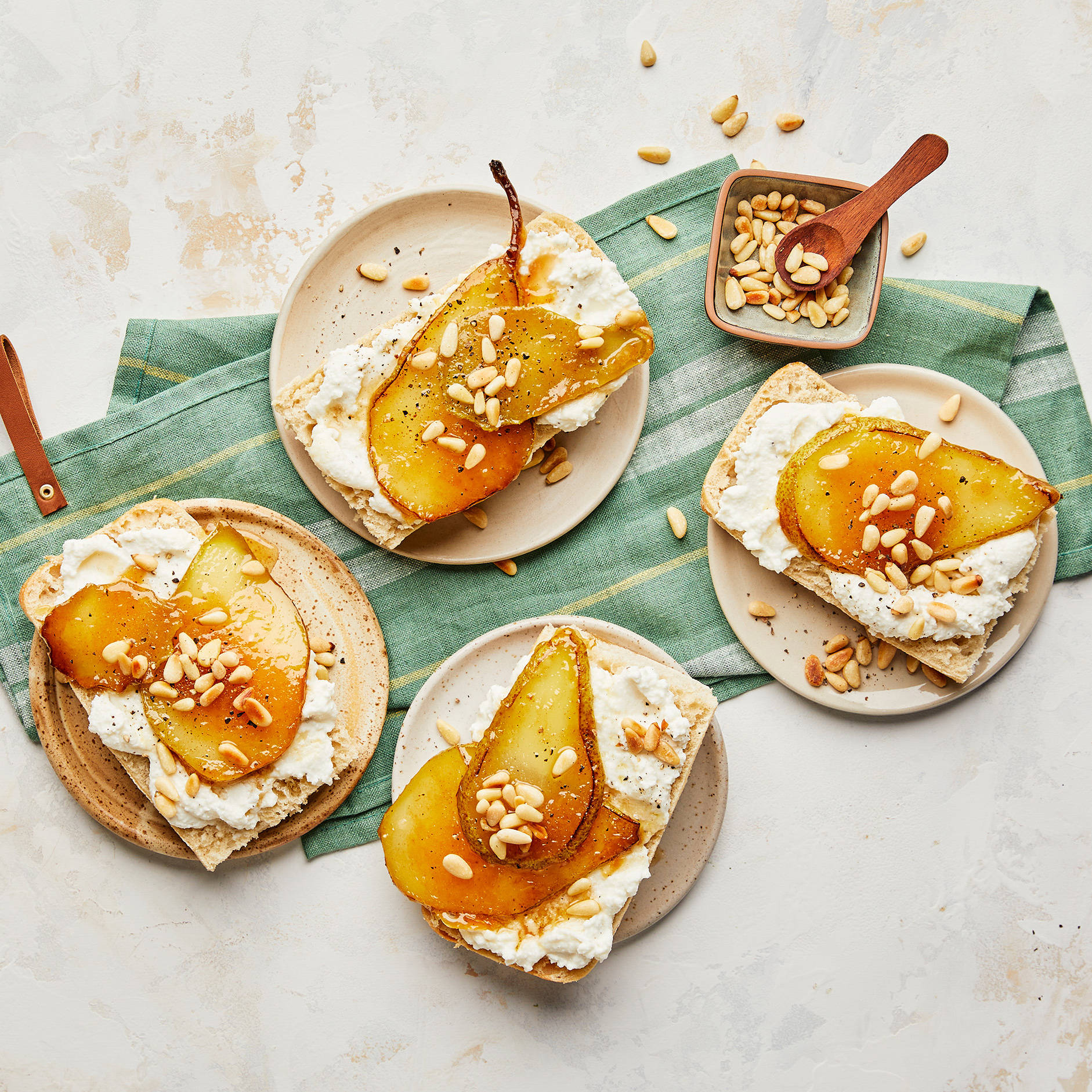 Karamellisierte Birnentoasts mit Frischkäse und Pinienkernen.