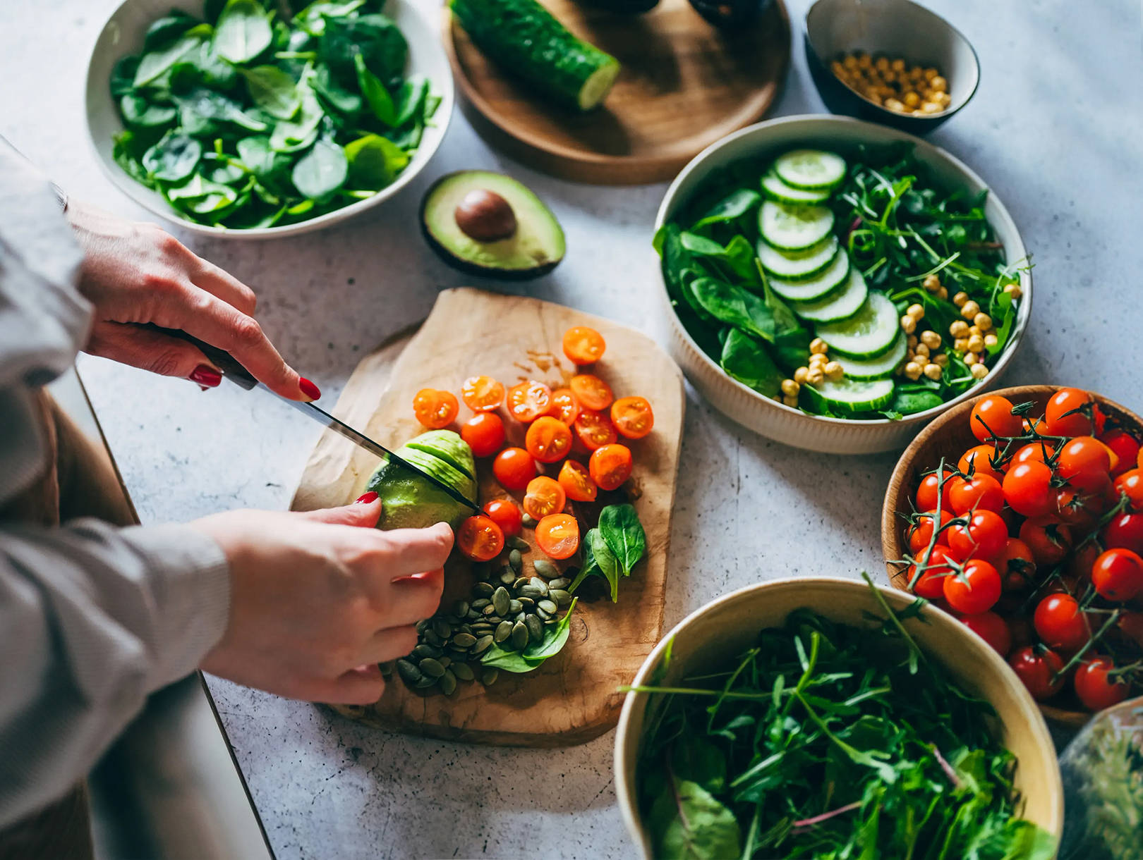 Zubereitung eines frischen Gemüsesalats mit Avocado und Blattgemüse.