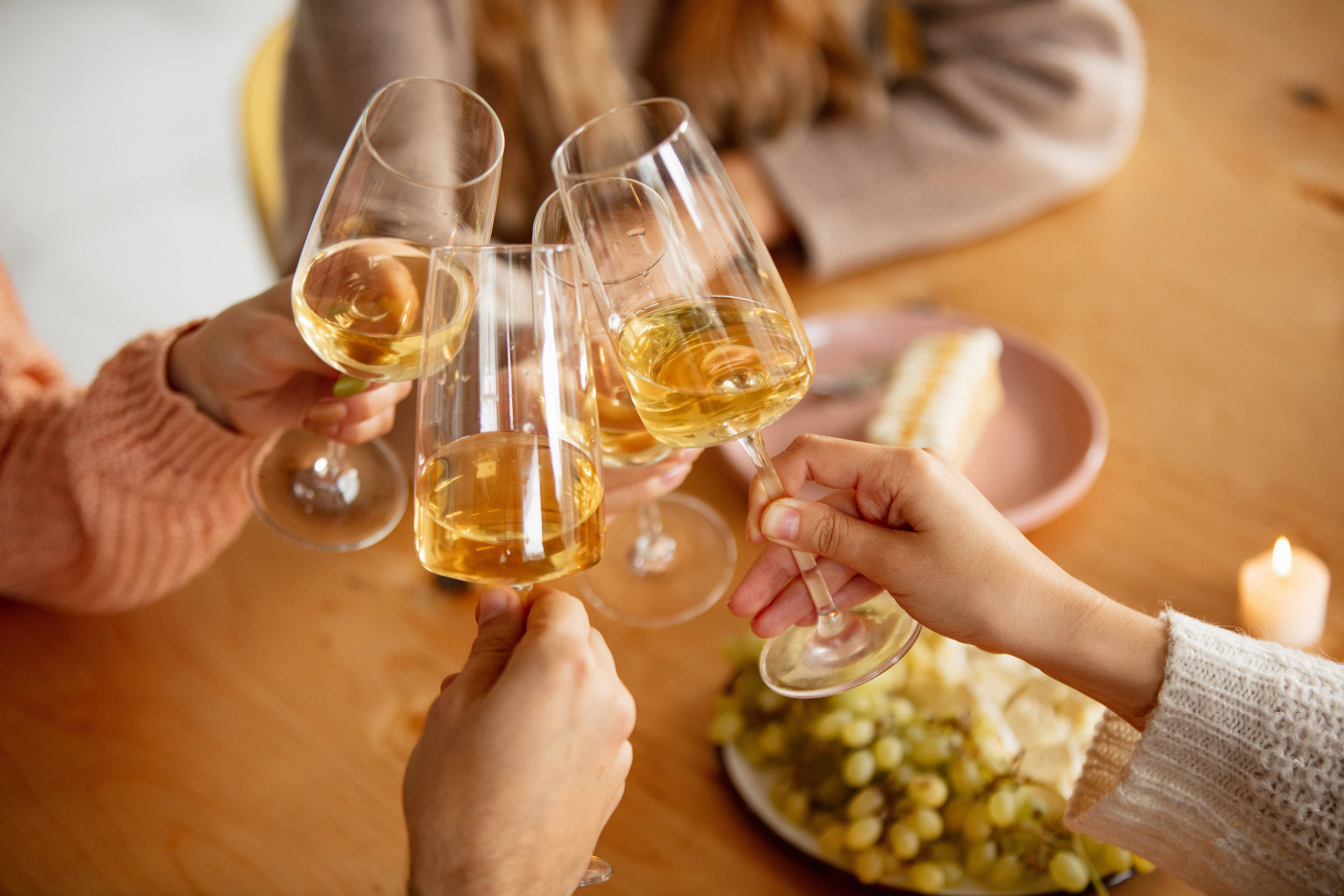 Freunde stoßen mit Weißwein an einem Tisch an.