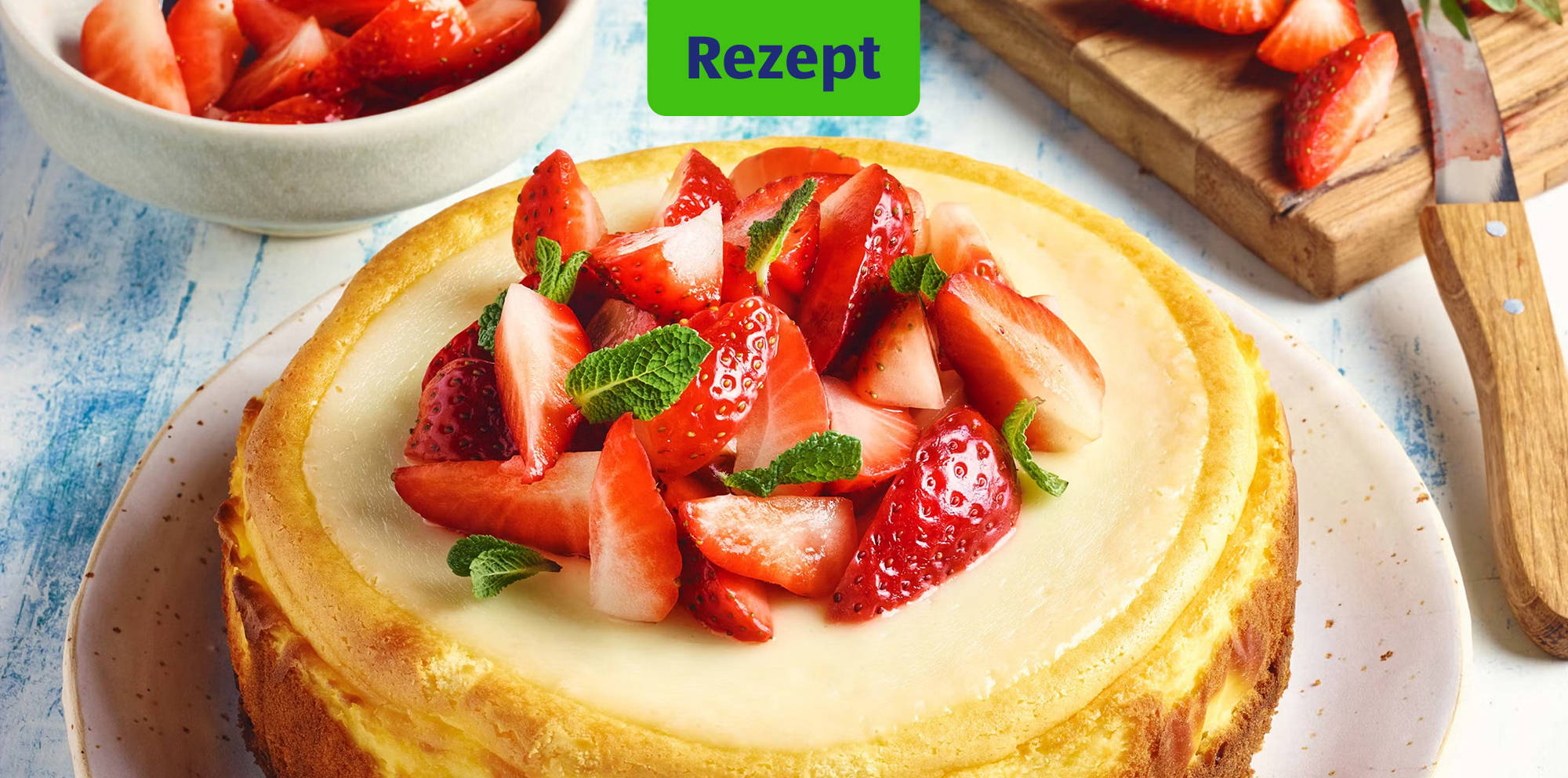 Erdbeer‑Cheesecake mit frischer Minzgarnitur.