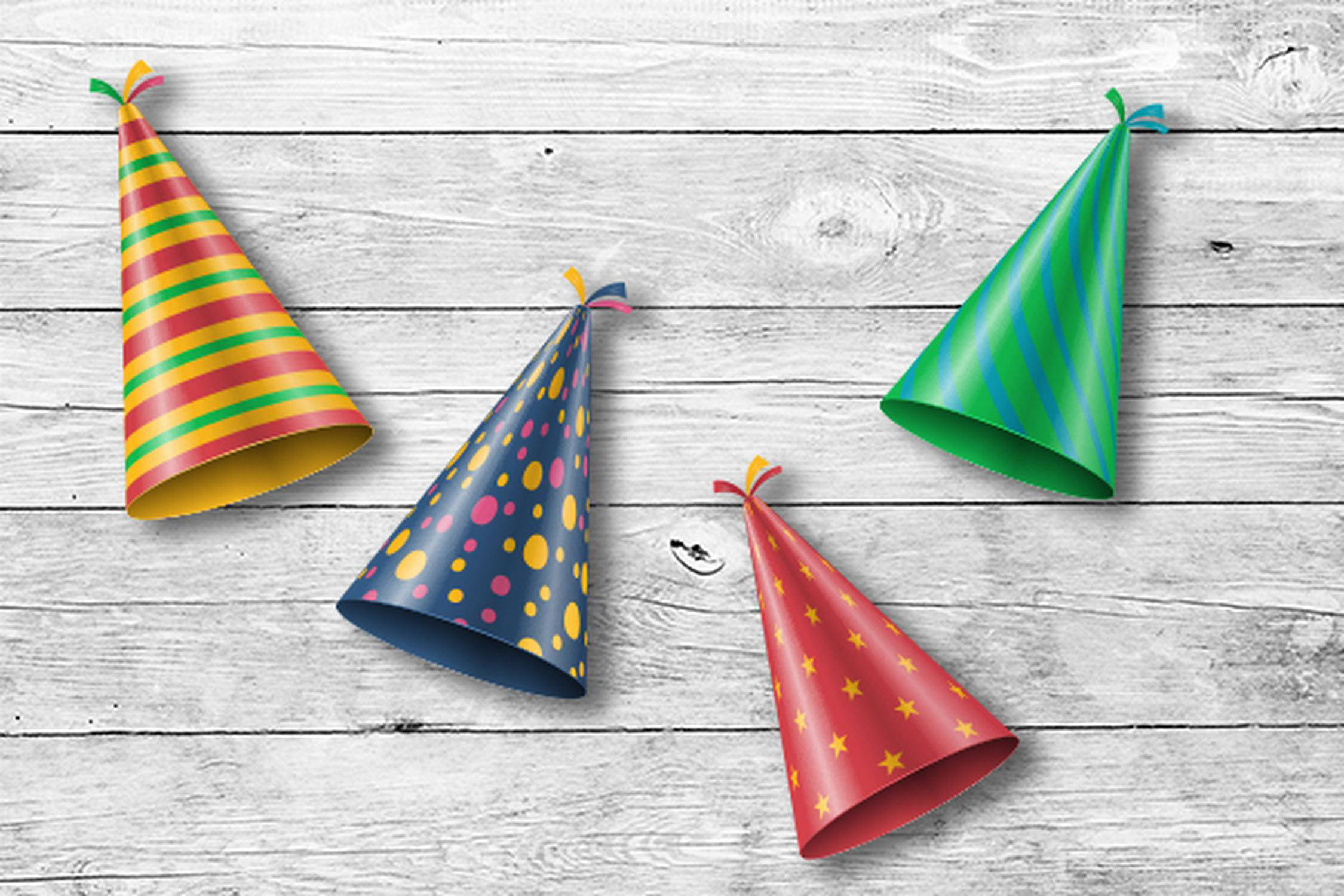 vier bunte Partyhüte liegen auf einem Holzuntergrund nebeneinander