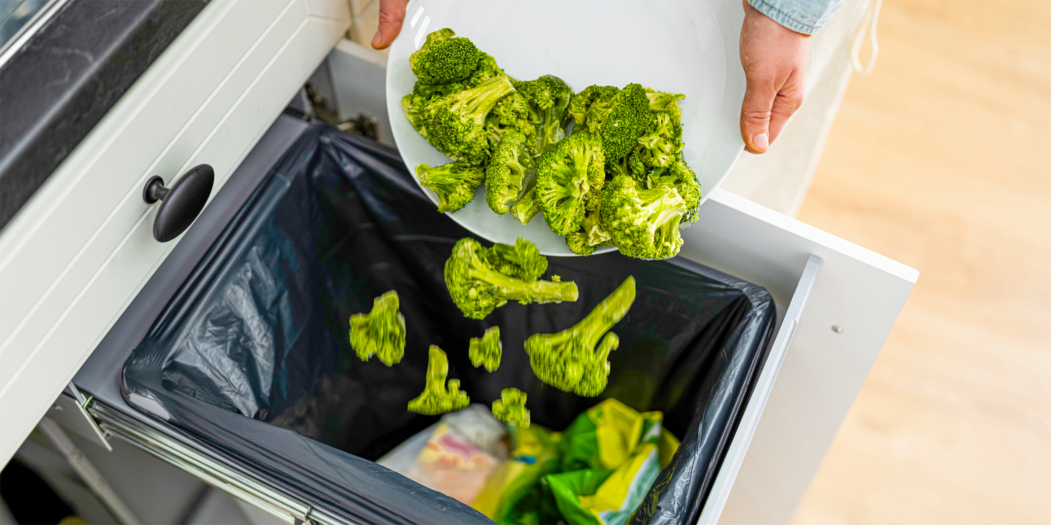 Eine Person leert eine große Portion noch essbarer Reste von Brokkoli in den Mülleimer.