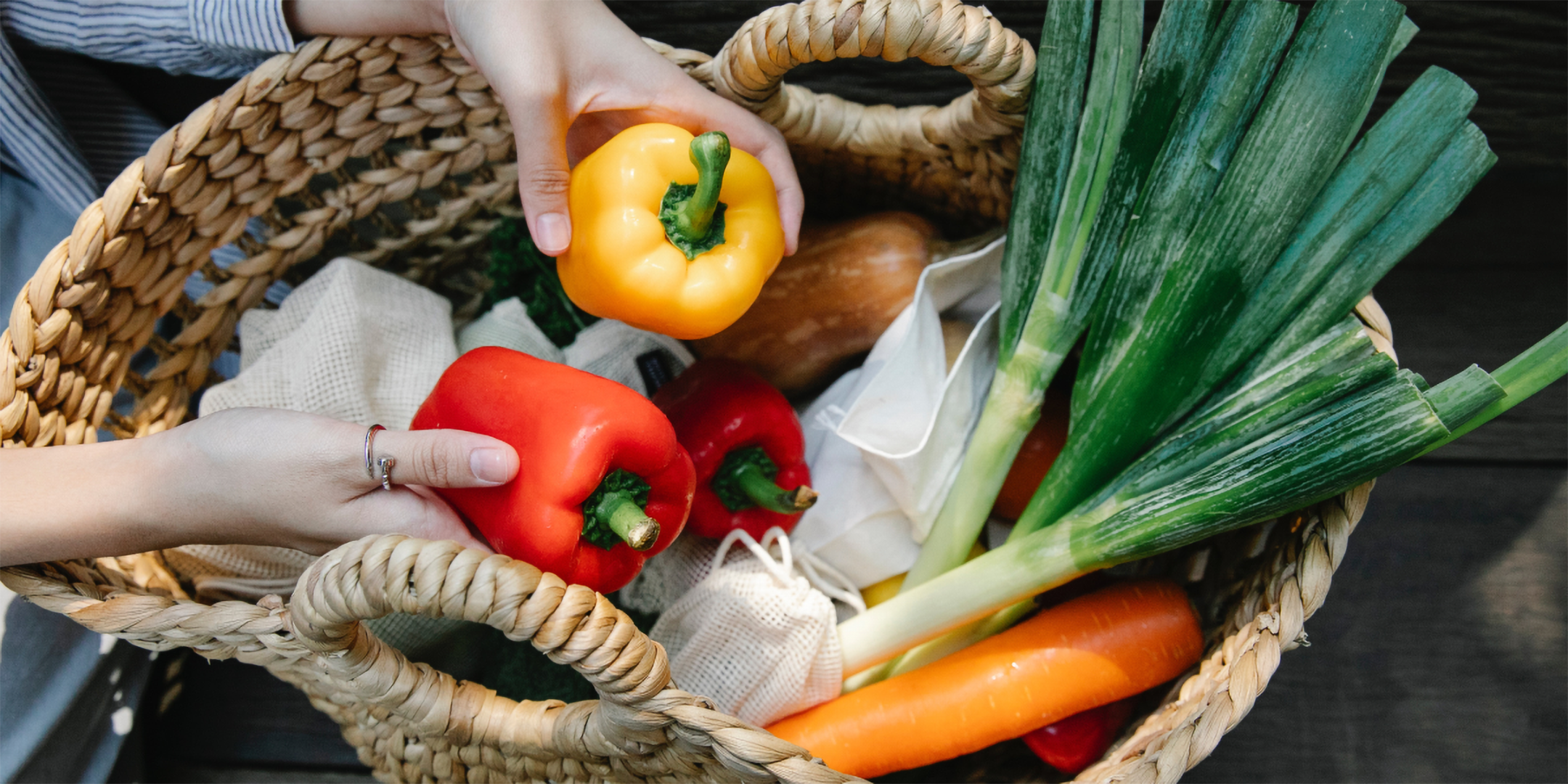 Hände nehmen Paprikas aus Korb mit Bio-Gemüse.