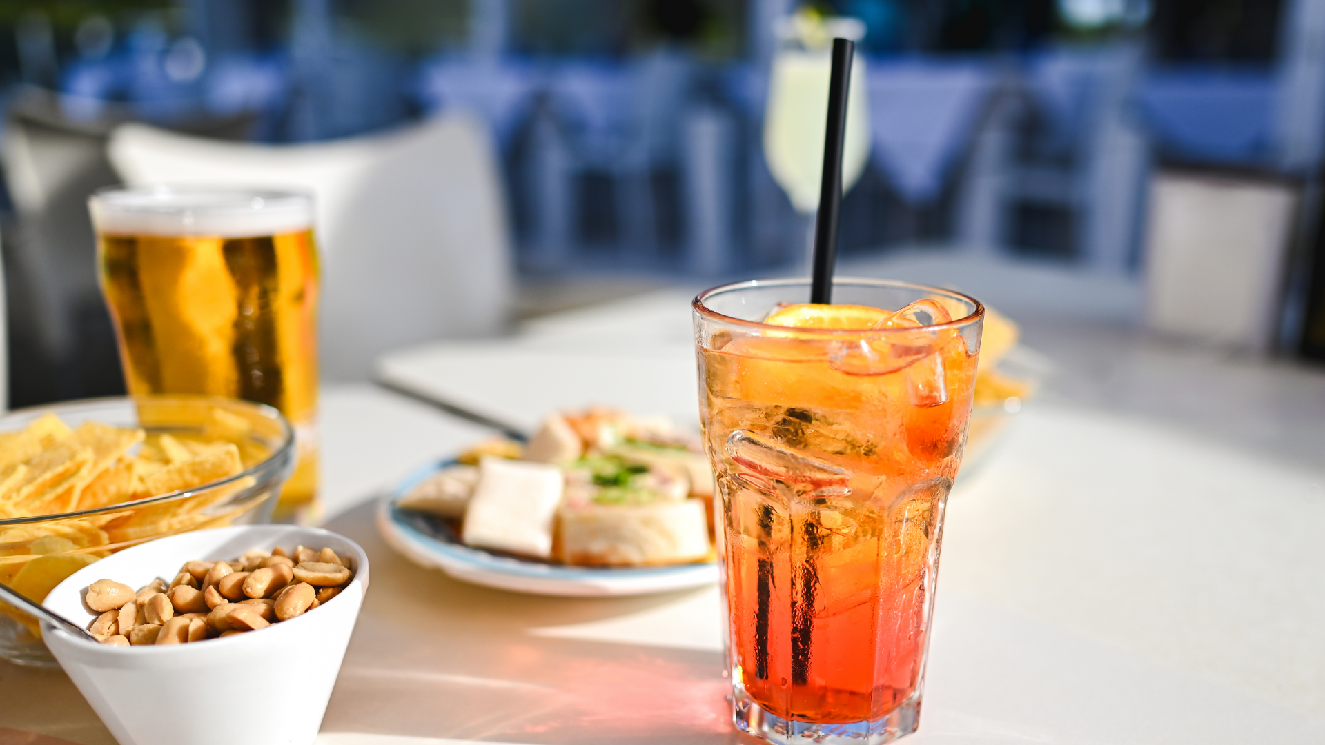 Aperitif, Bier, Snacks auf sonnigem Tisch im Freien.
