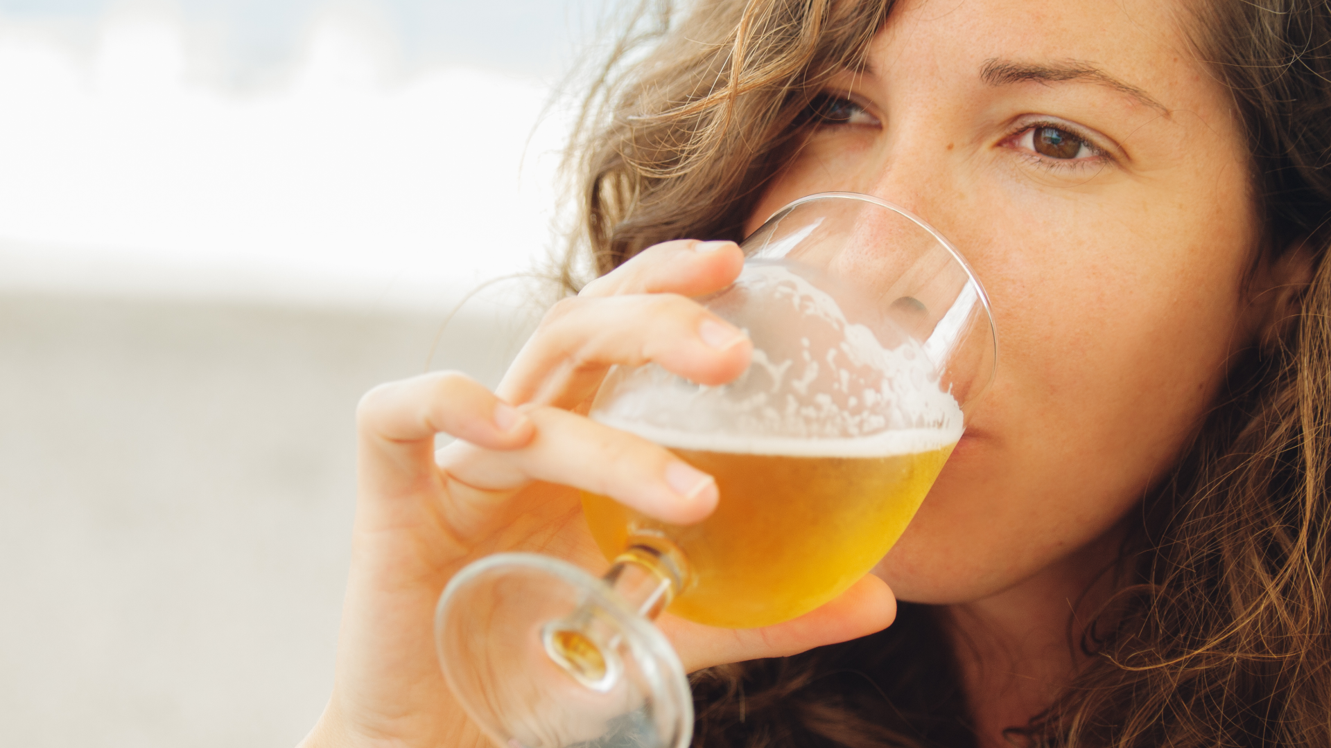 Frau trinkt Getränk aus einem Glas.