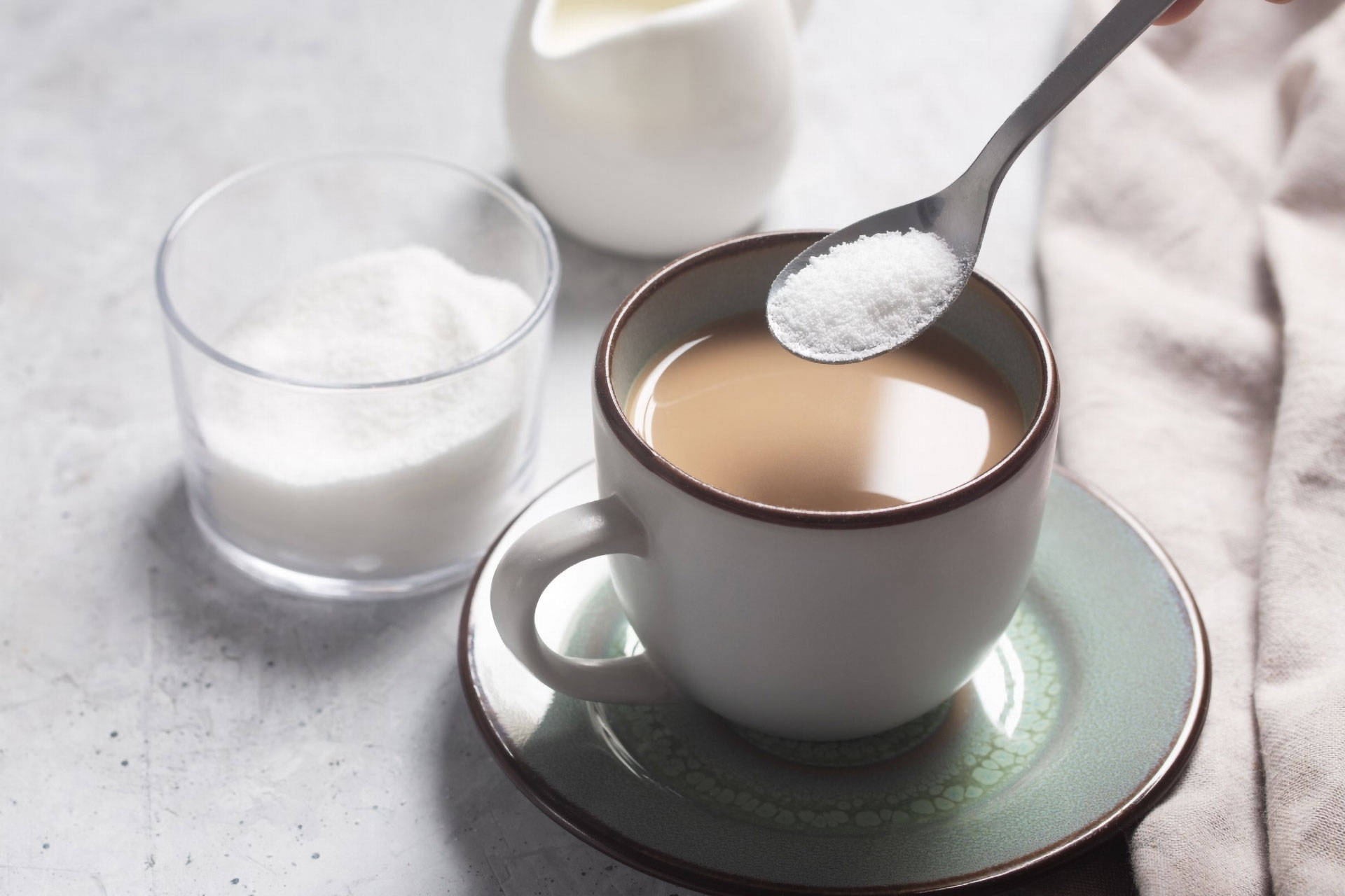 Jemand gibt weißen zuckerähnlichen Stoff Zucker mit einem Löffel in eine Tasse Kaffee.