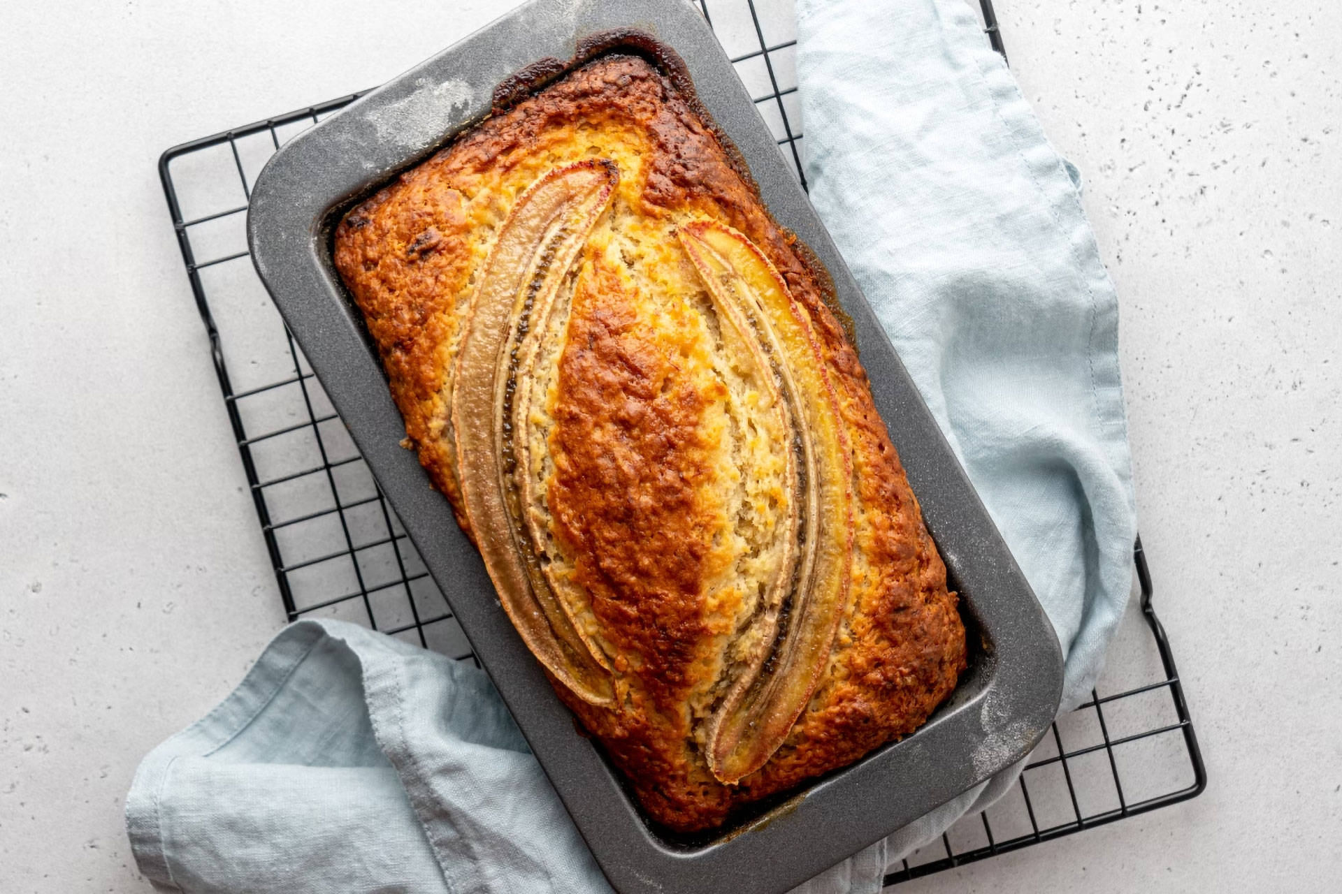 Frisch gebackenes Bananenbrot in einer Backform auf einem Kühlgitter.