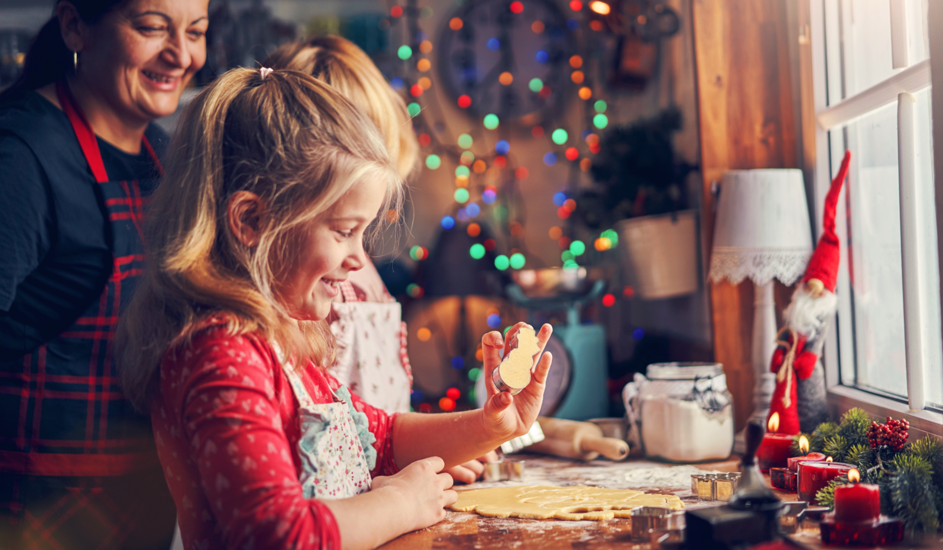 Mädchen backt lachend Plätzchen mit Schneemann-Ausstechform.