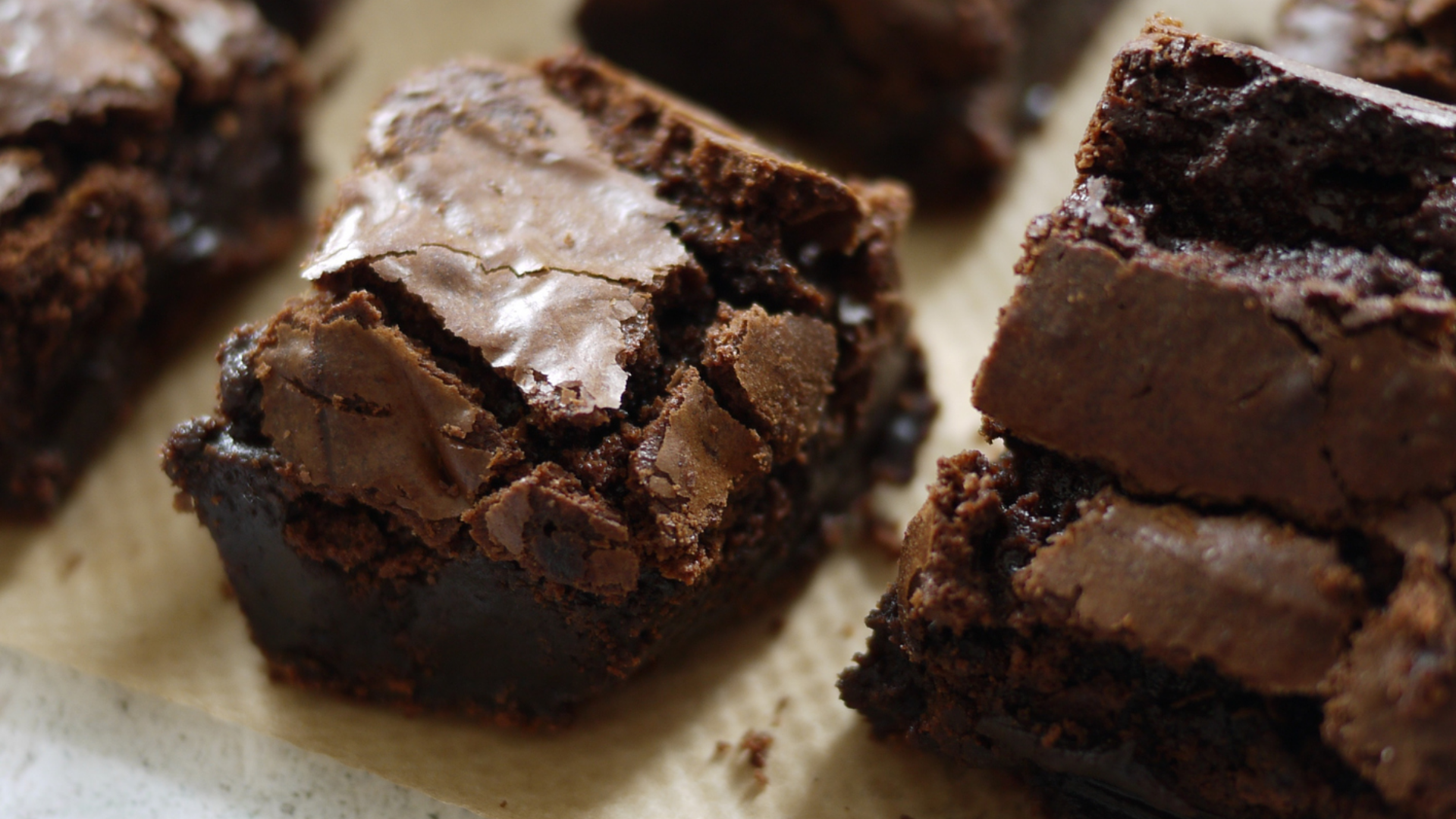 Nahaufnahme von saftigen, dunklen Schokoladen Brownies auf Papier.