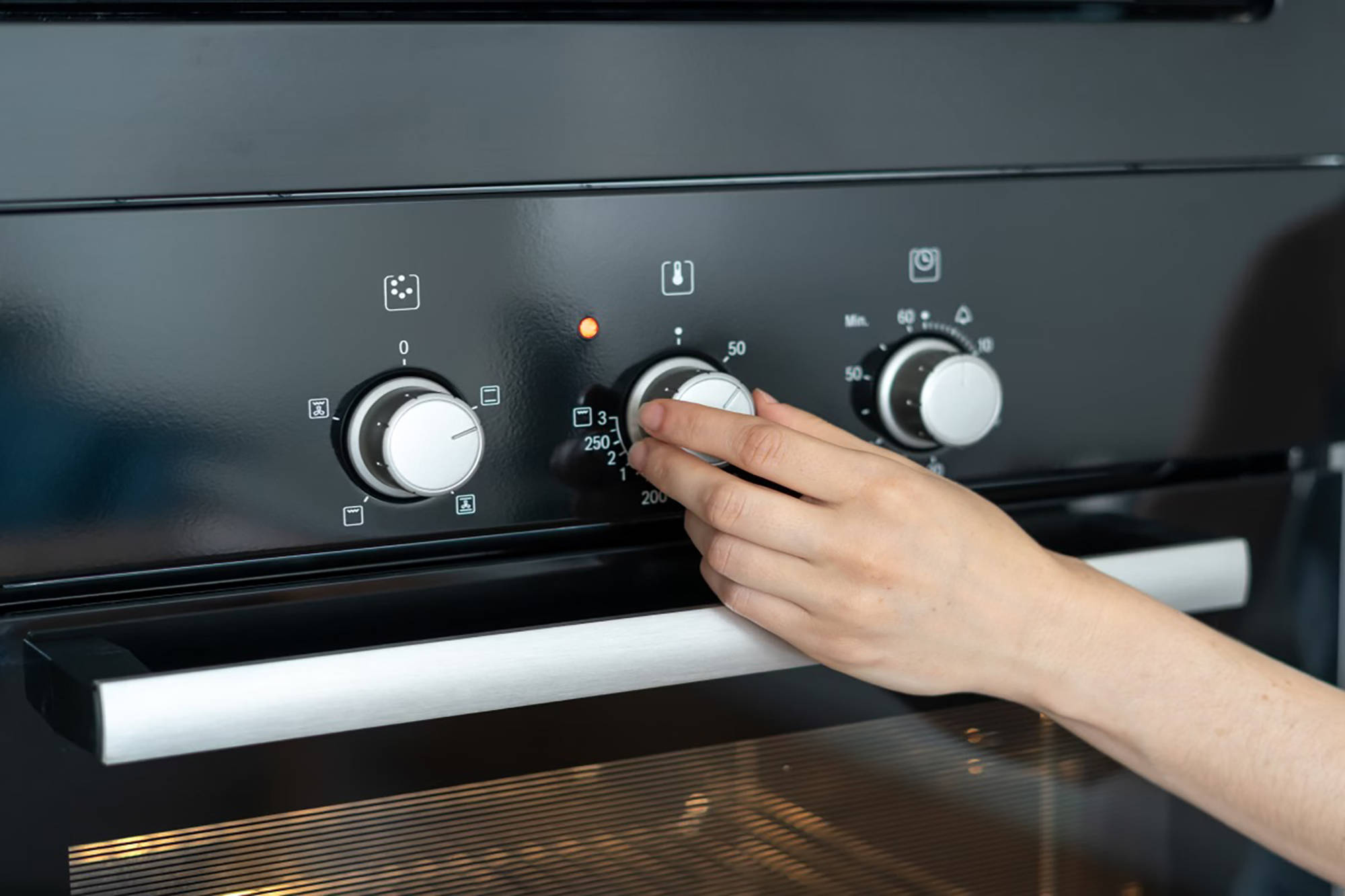 Hand dreht Regler am Backofen.