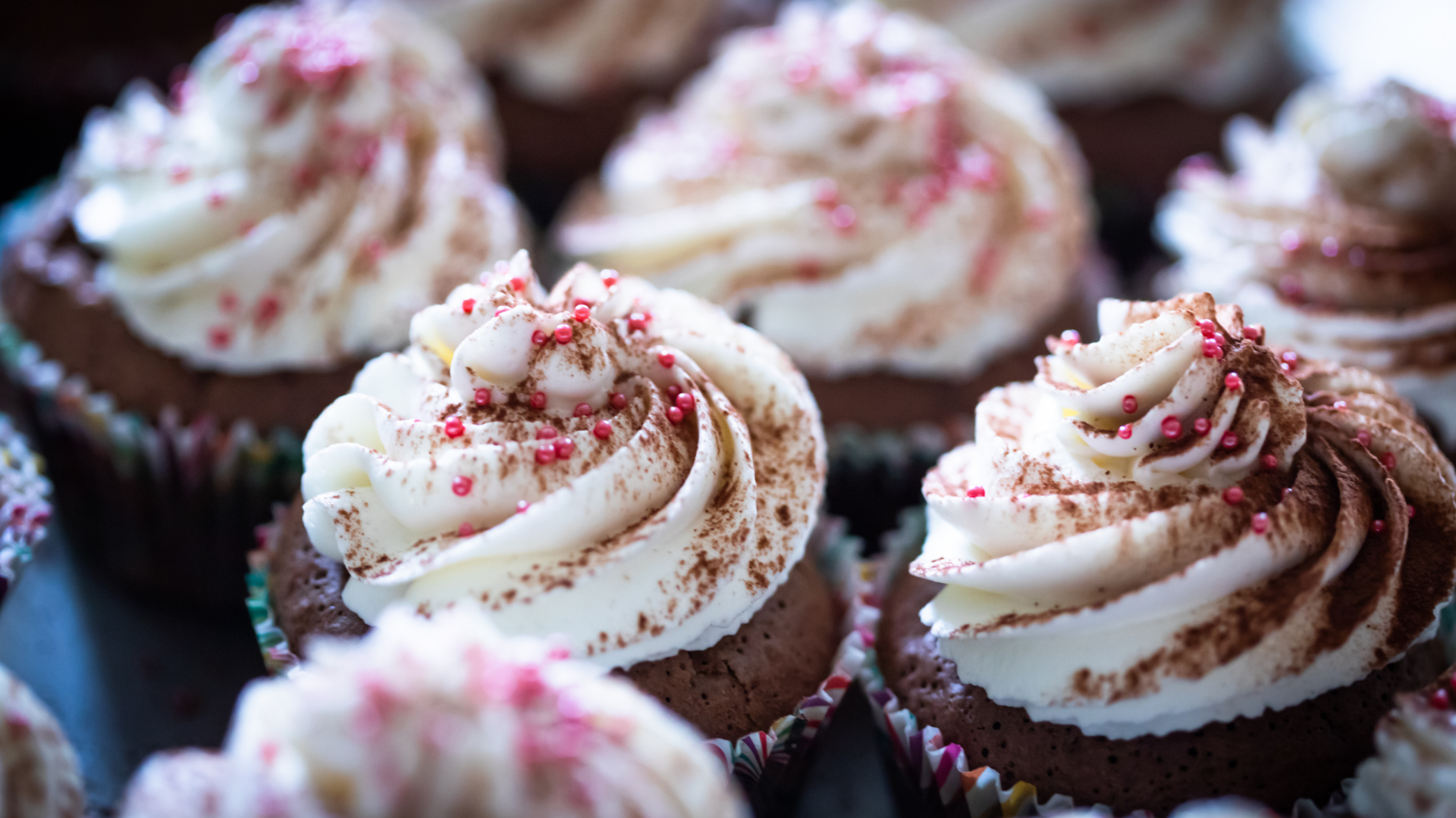 Schokoladenmuffins mit weißem Zuckerguss und rotem Streusel.