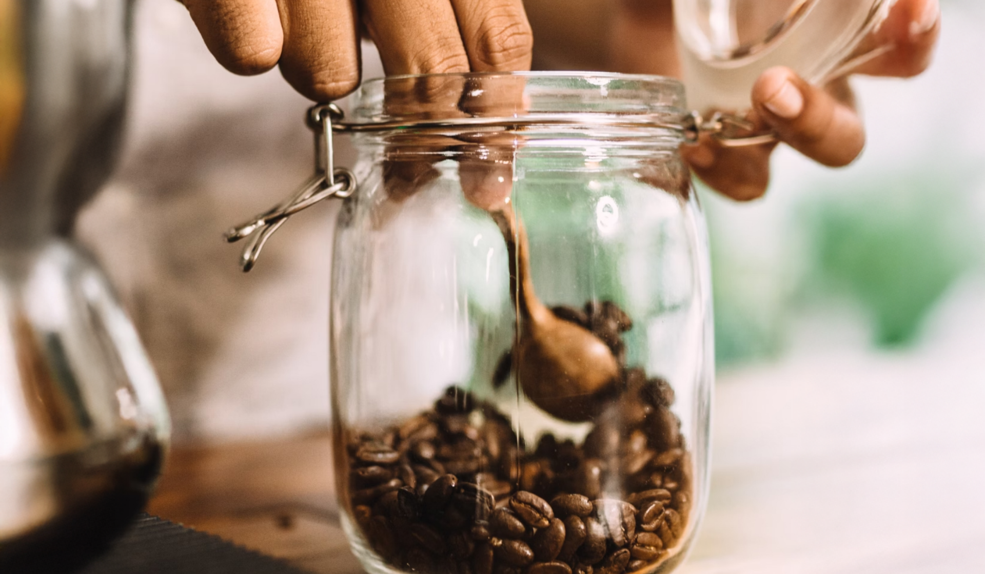 Eine Person nimmt geröstete Kaffeebohnen aus einem Einmachglas.