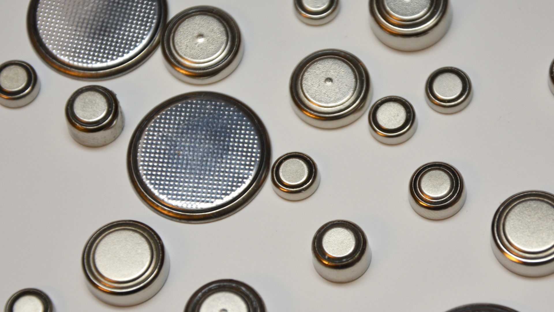 Mehrere Knopfzellen unterschiedlicher Größe auf weißem Hintergrund.