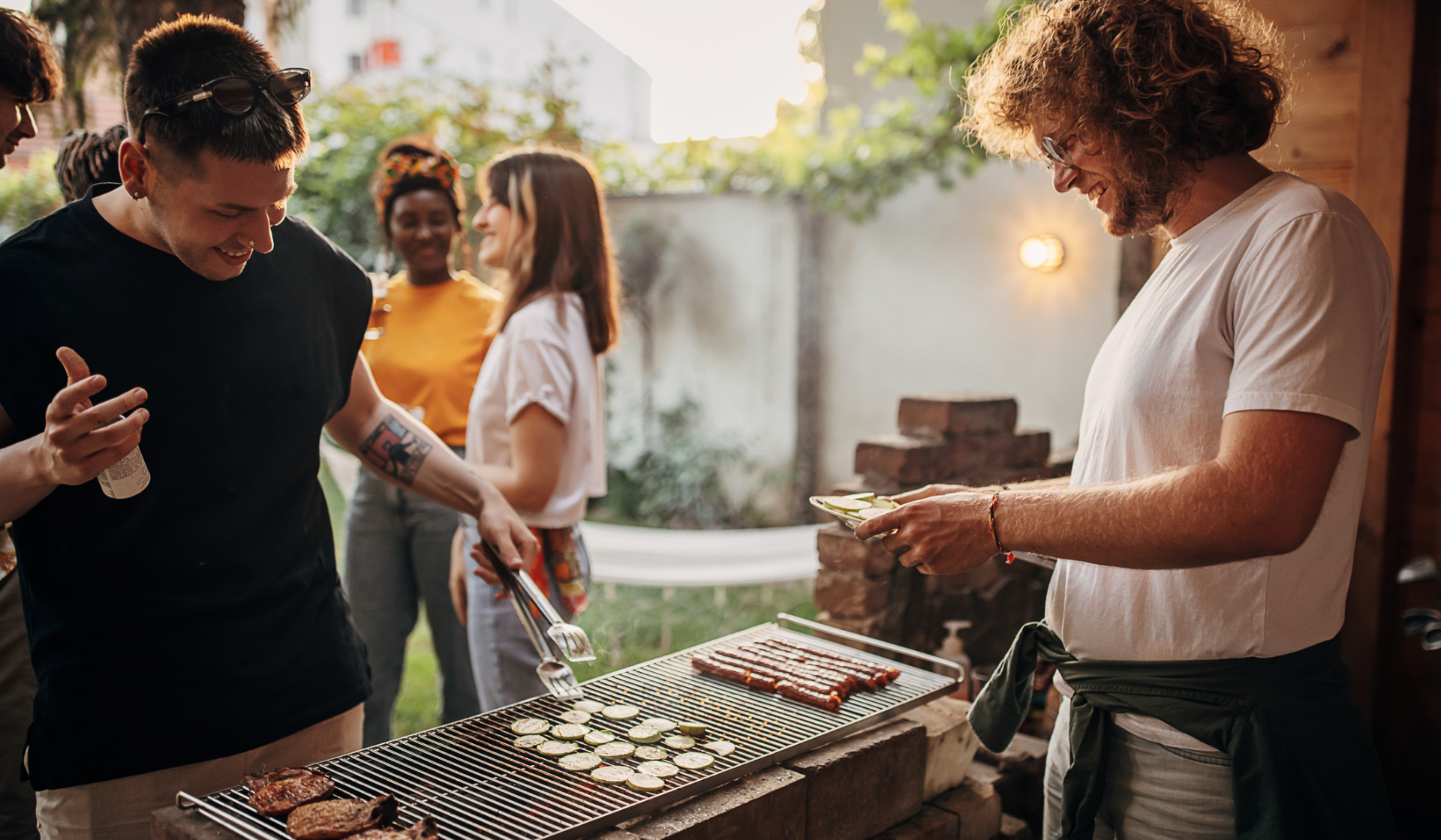 Freunde grillen gemeinsam Zucchini und Würstchen.