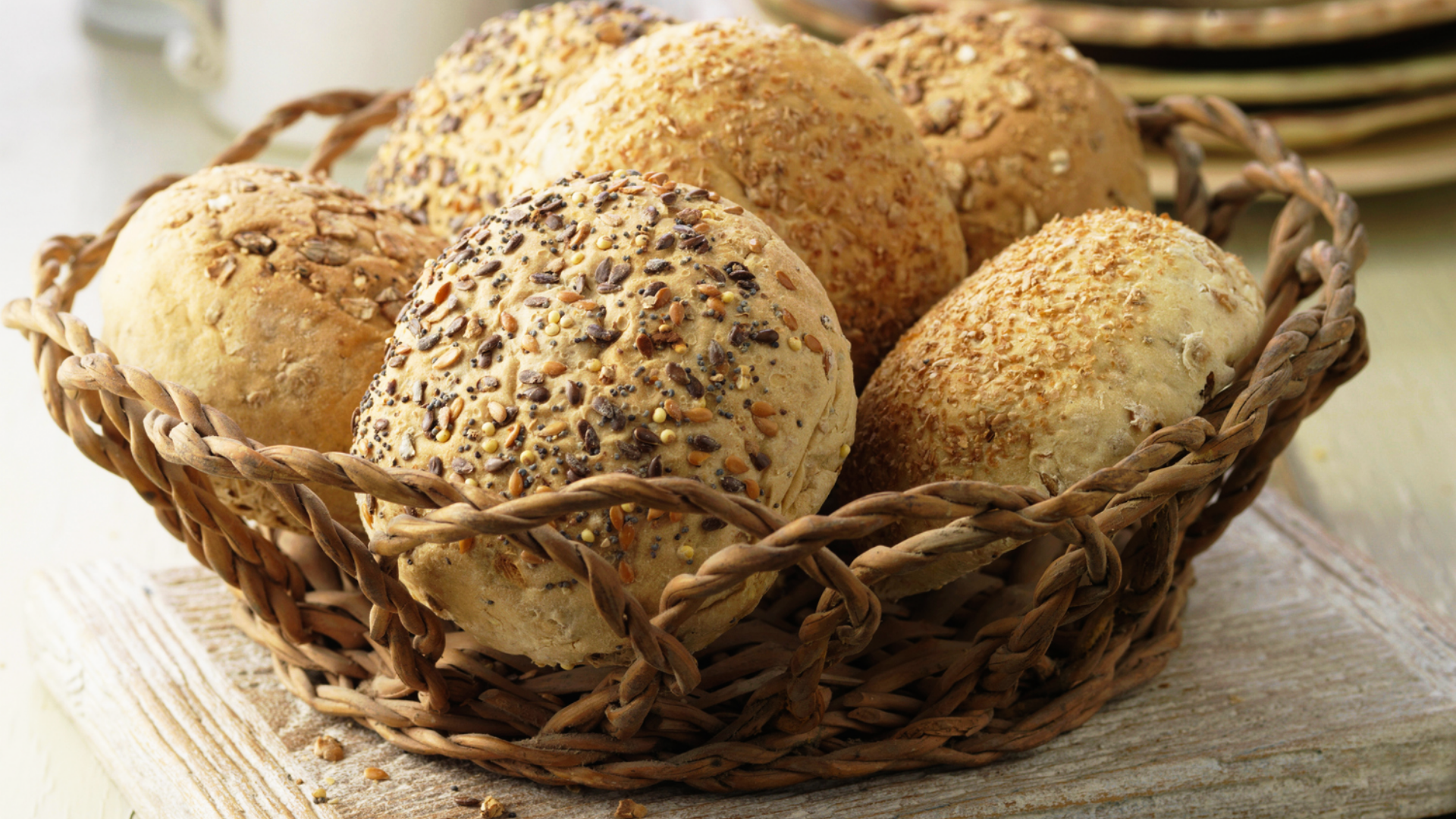 Geflochtener Korb mit verschiedenen Brötchen und Saaten.
