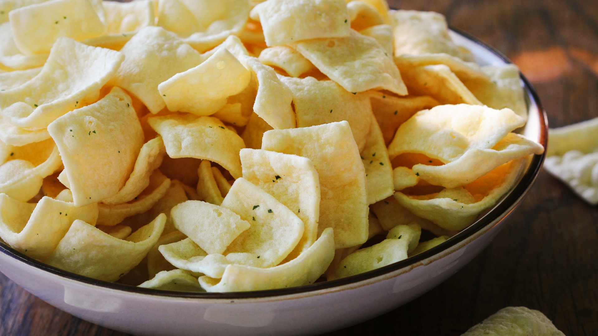 Schale voller blassgelber, rechteckiger Chips mit Kräutern.