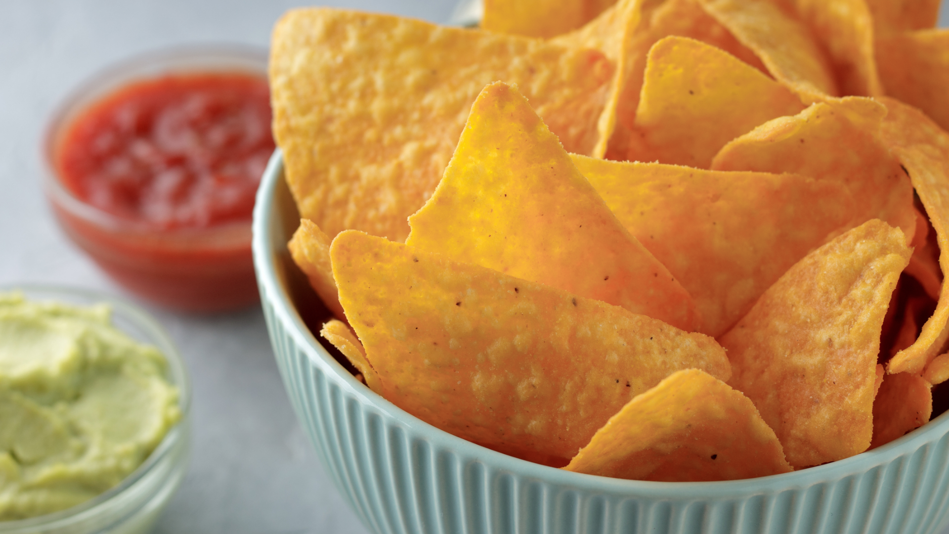 Schale mit Tortilla-Chips, Guacamole und Salsa im Hintergrund.